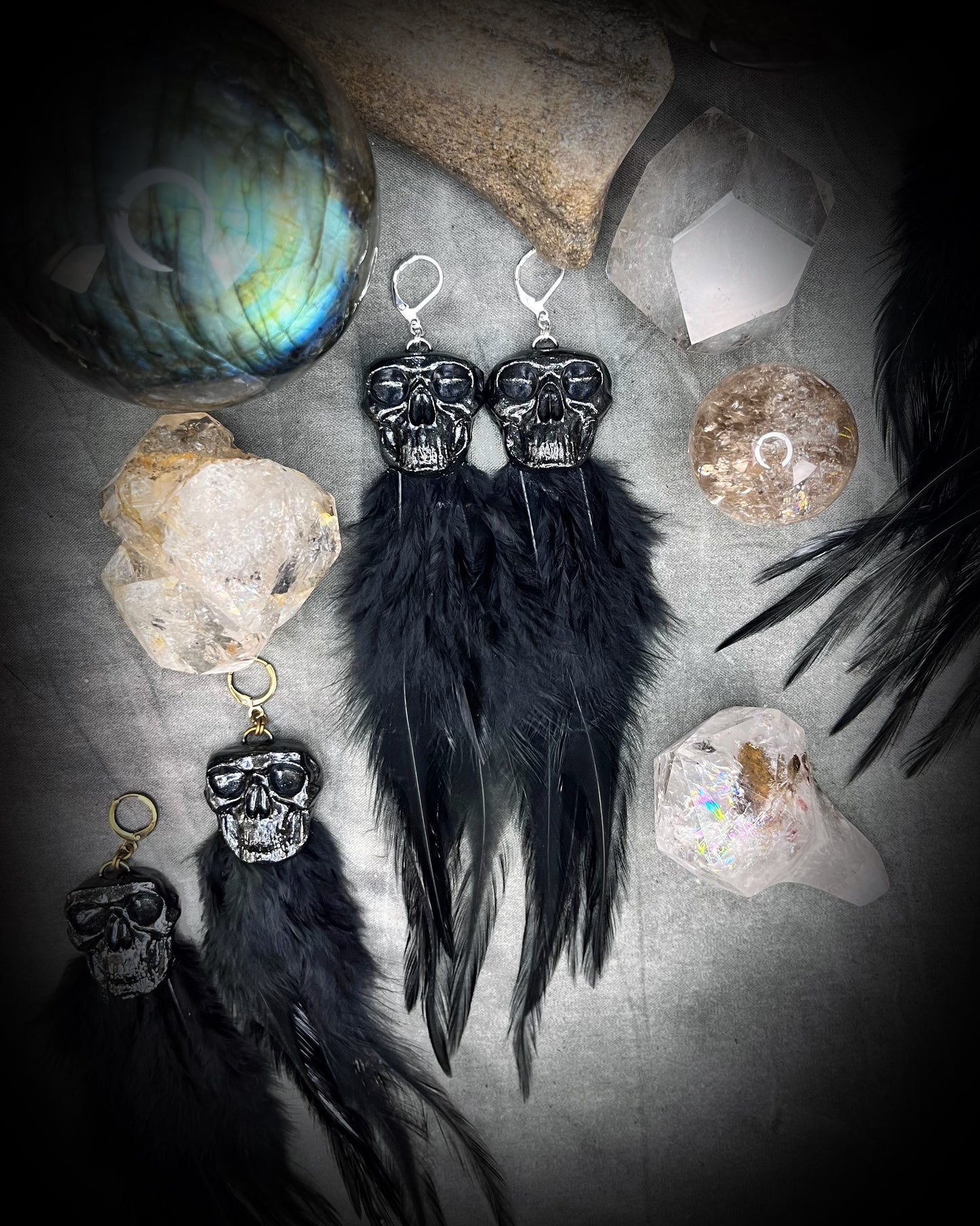 Handmade black skull and black feather earrings in a vintage inspired brass or sterling silver huggy earring style. Witchy and boho style meets gothic elegance.