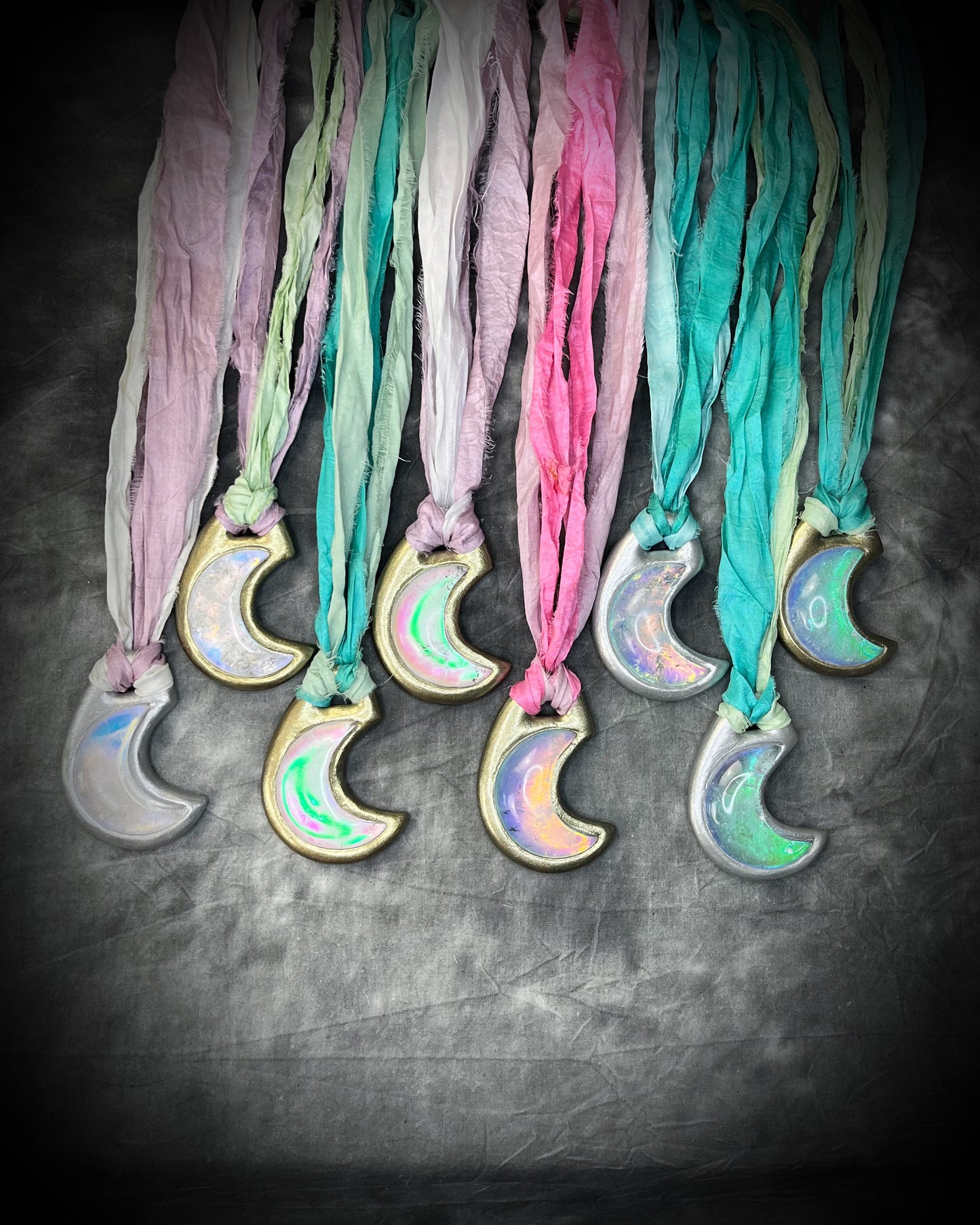 Multiple opalescent crescent moon quartz gemstone handmade crystal healing jewelry necklaces on recycled silk in shades of pink, mint green, turquoise, lilac and finished in gold or silver. All with eco-friendly recycled silk and an opal pendant glow.