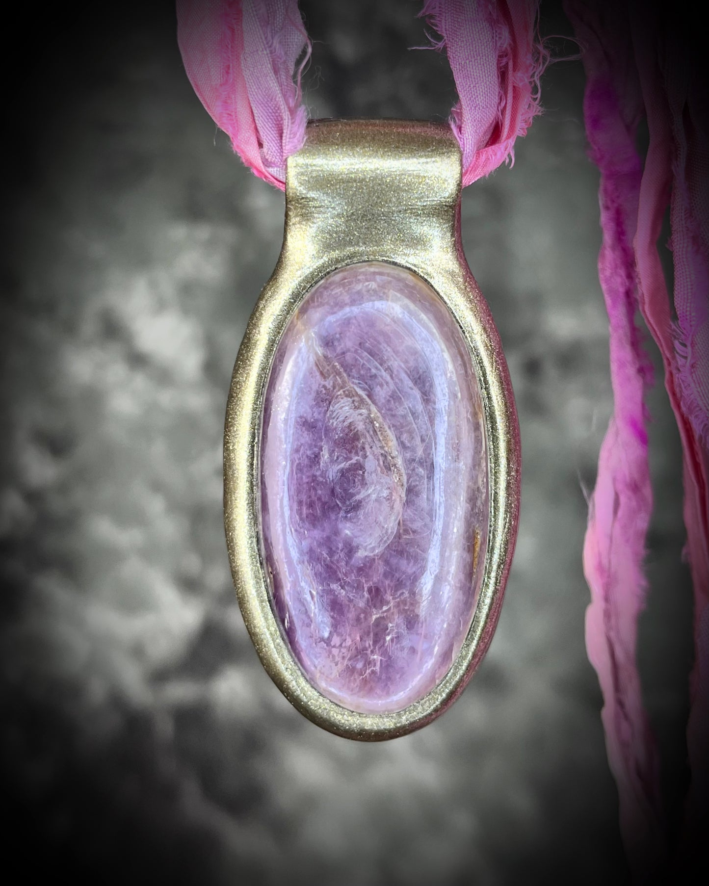 Handmade designer anti-anxiety crystal lepidolite raw stone necklace in gold finish. This gemstone pendant is hung from pink recycled silk for a vibrant and sustainable elegance.