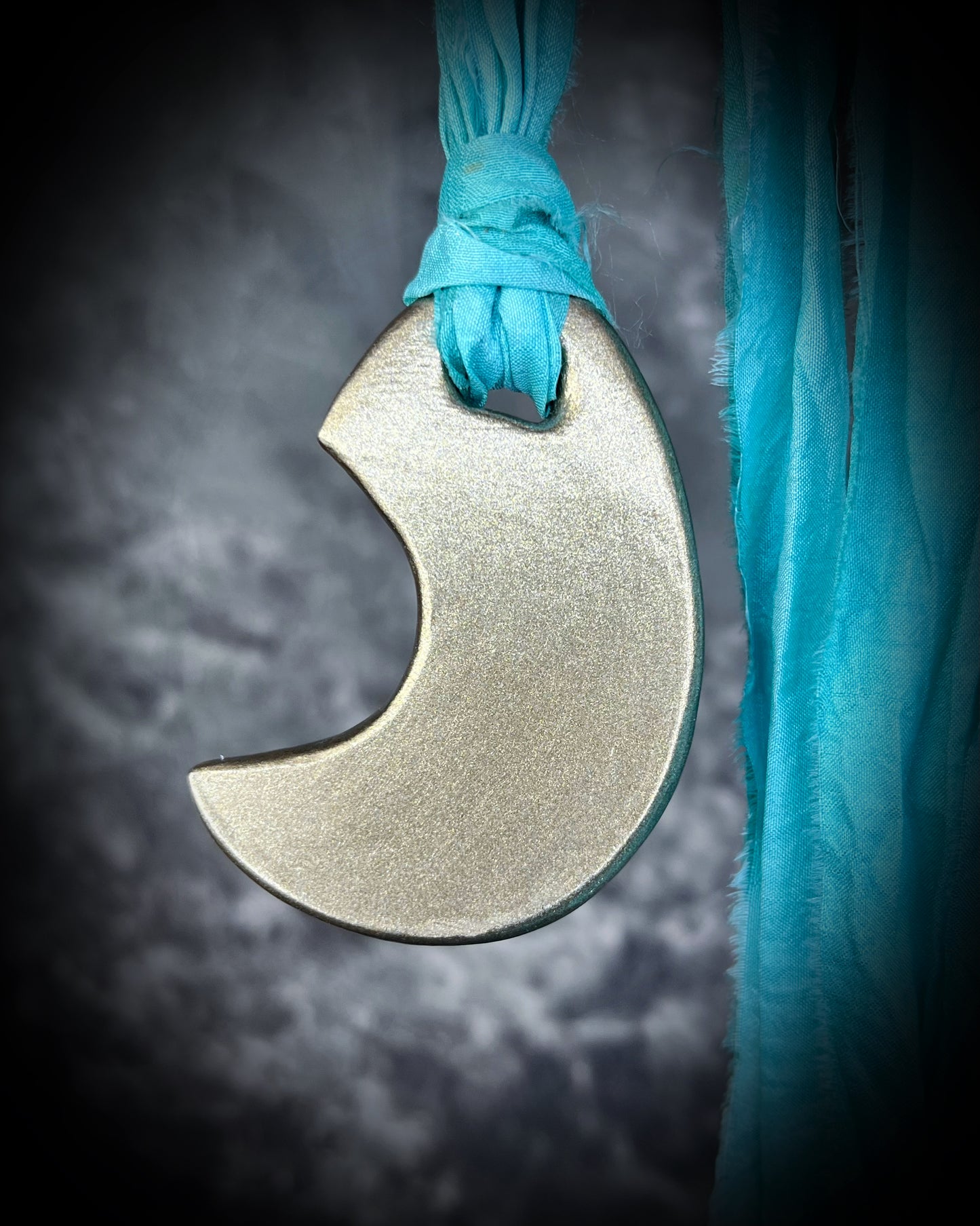 Back view of handcrafted designer opalescent turquoise quartz gemstone crescent moon pendant in a gold finish hung from aqua recycled silk for a sustainable and eco-friendly mystic.