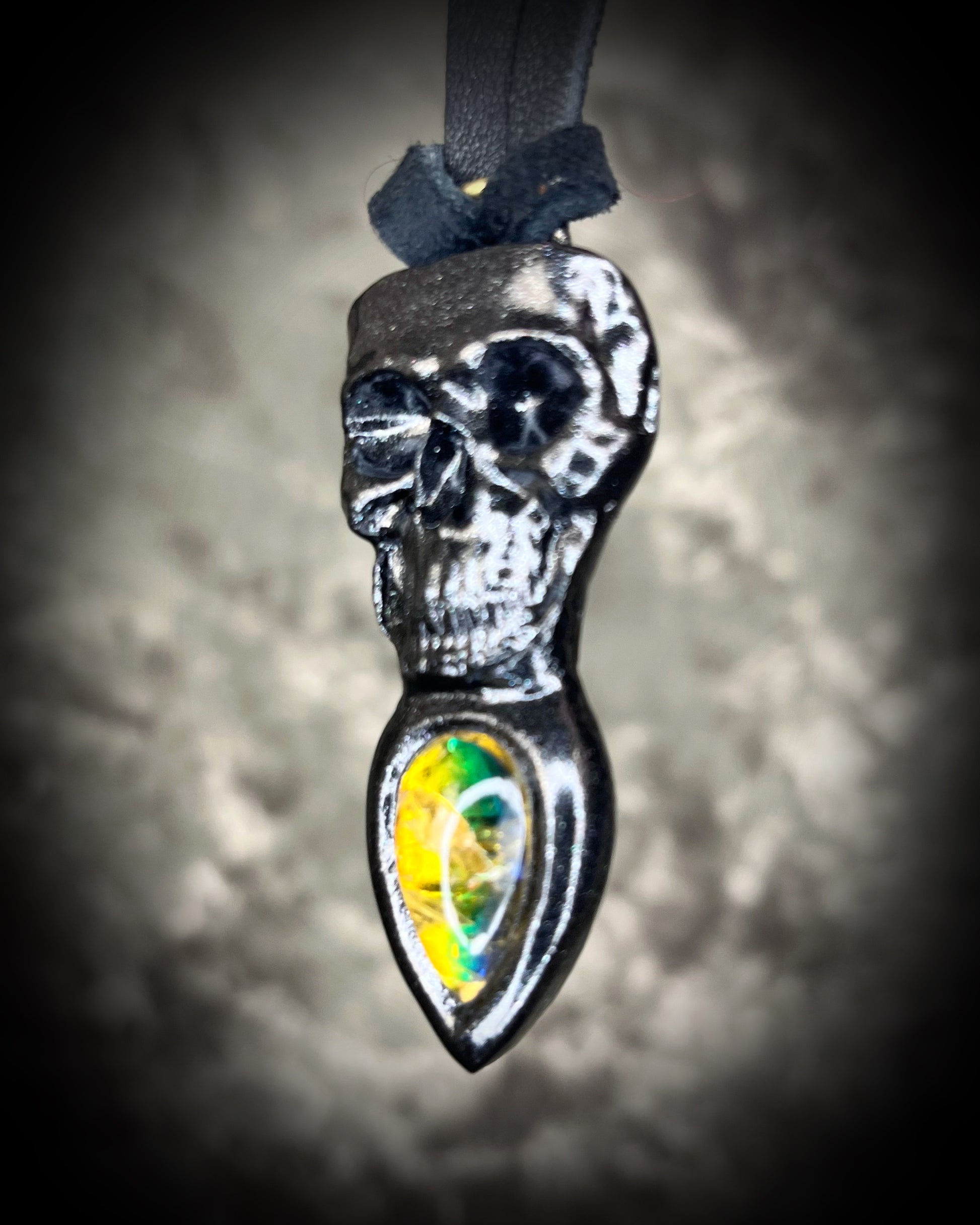 Skull-shaped pendant with a yellow fire citrine teardrop shaped gemstone on a dark background. Halloween jewelry for her, gothic jewelry gift for her.