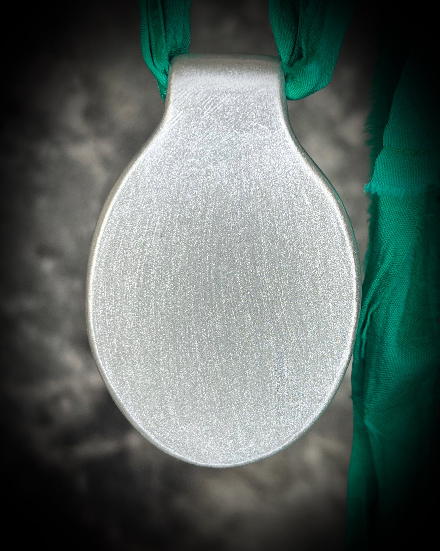 Back of handmade chrysocolla crystal on recycled silk cord necklace styled on neutral background.