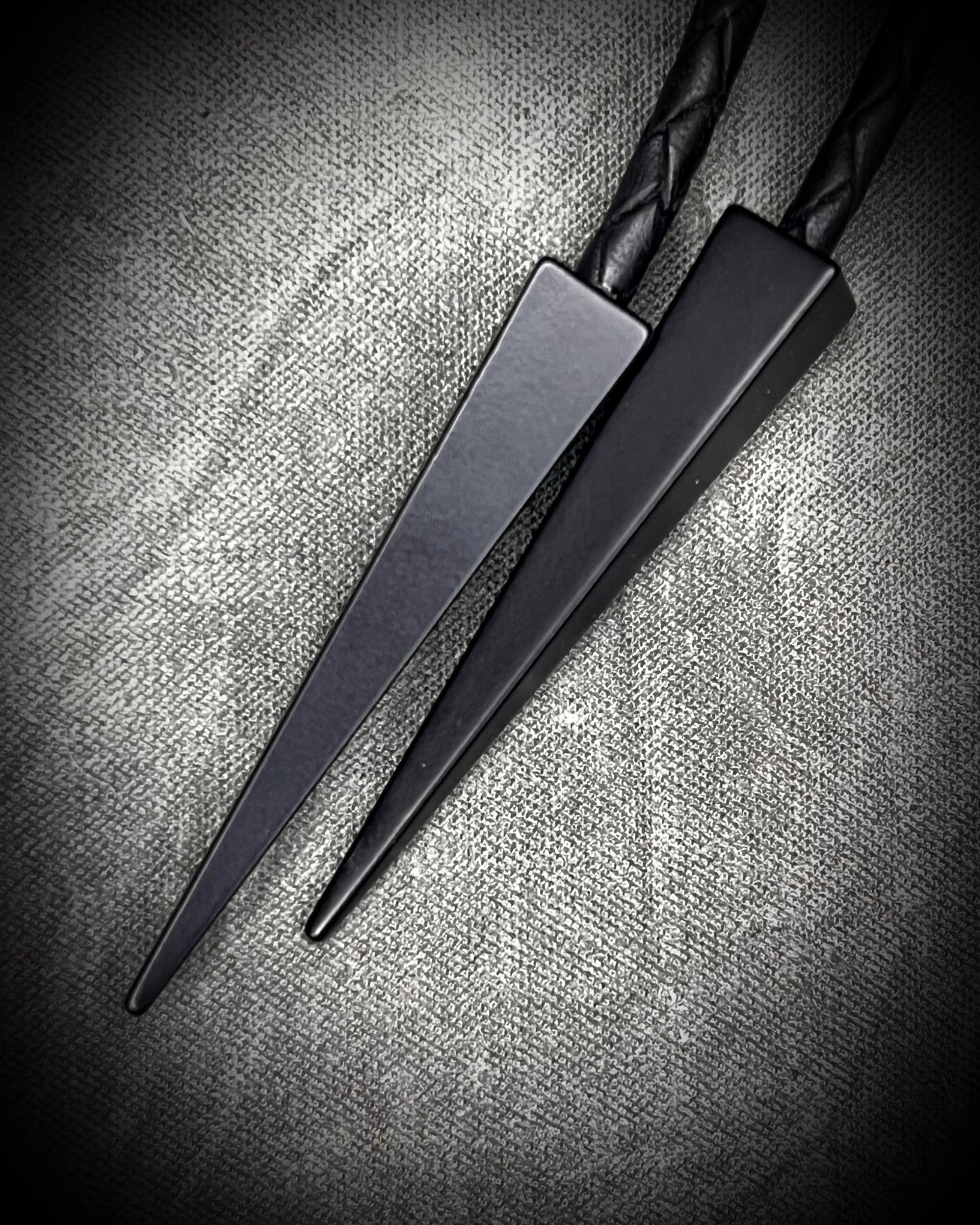 Closeup of sblack bolo tips on Indonesian Amber XL black on black bolo tie with black spike tips. Western Gothic fantasy jewelry for 2026 fashion trends and gift for him or her.