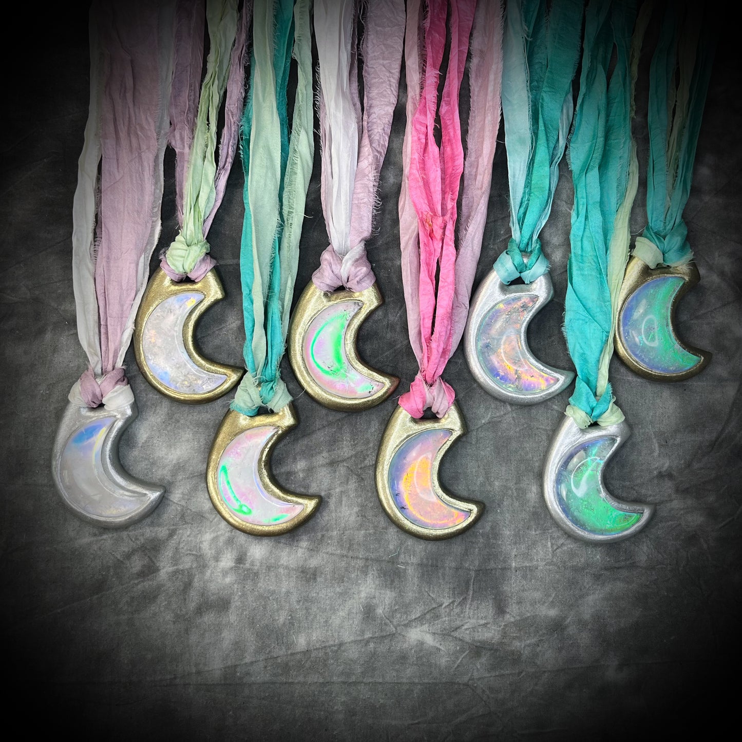 Multiple opalescent crescent moon quartz gemstone handmade crystal healing jewelry necklaces on recycled silk in shades of pink, mint green, turquoise, lilac and finished in gold or silver. All with eco-friendly recycled silk and an opal pendant glow.
