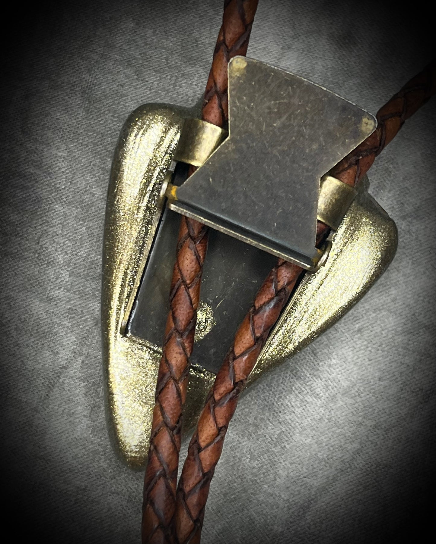Fossilized mastodon tooth enamel bolo tie showing the natural molar crown edge, with brown leather, gold finish and gold spike tips.