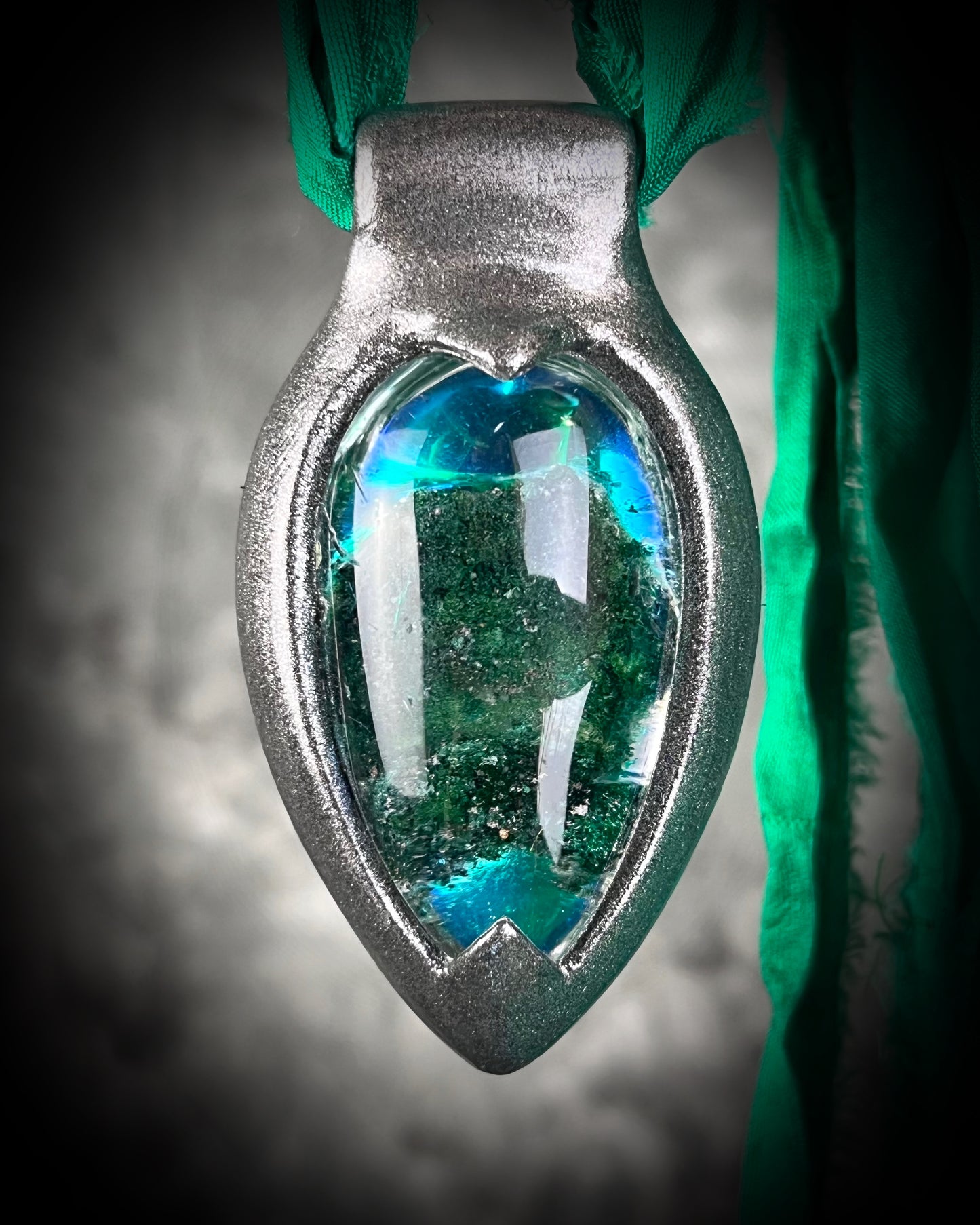 Chlorite Included Quartz necklace in a dark silver gunmetal finish on emerald green recycled silk, glowing with natural green mosslike crystal inclusions.