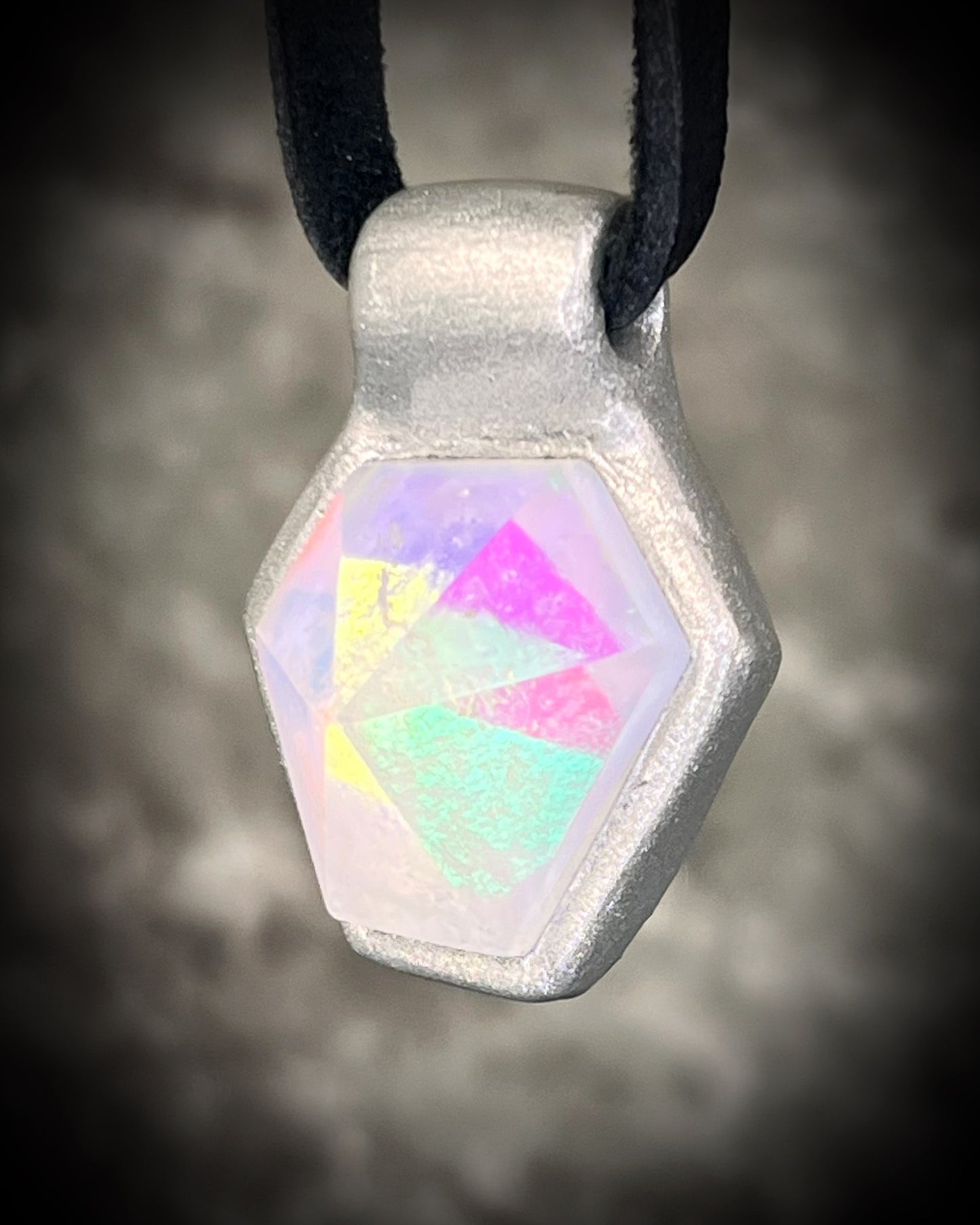 Handmade clear quartz crystal necklace with an opalescent flash that feels enchanted from another realm. Framed in silver in a hexagon shape and hung from black leather, this pendant feels cinematic, and like an unearthed treasure.