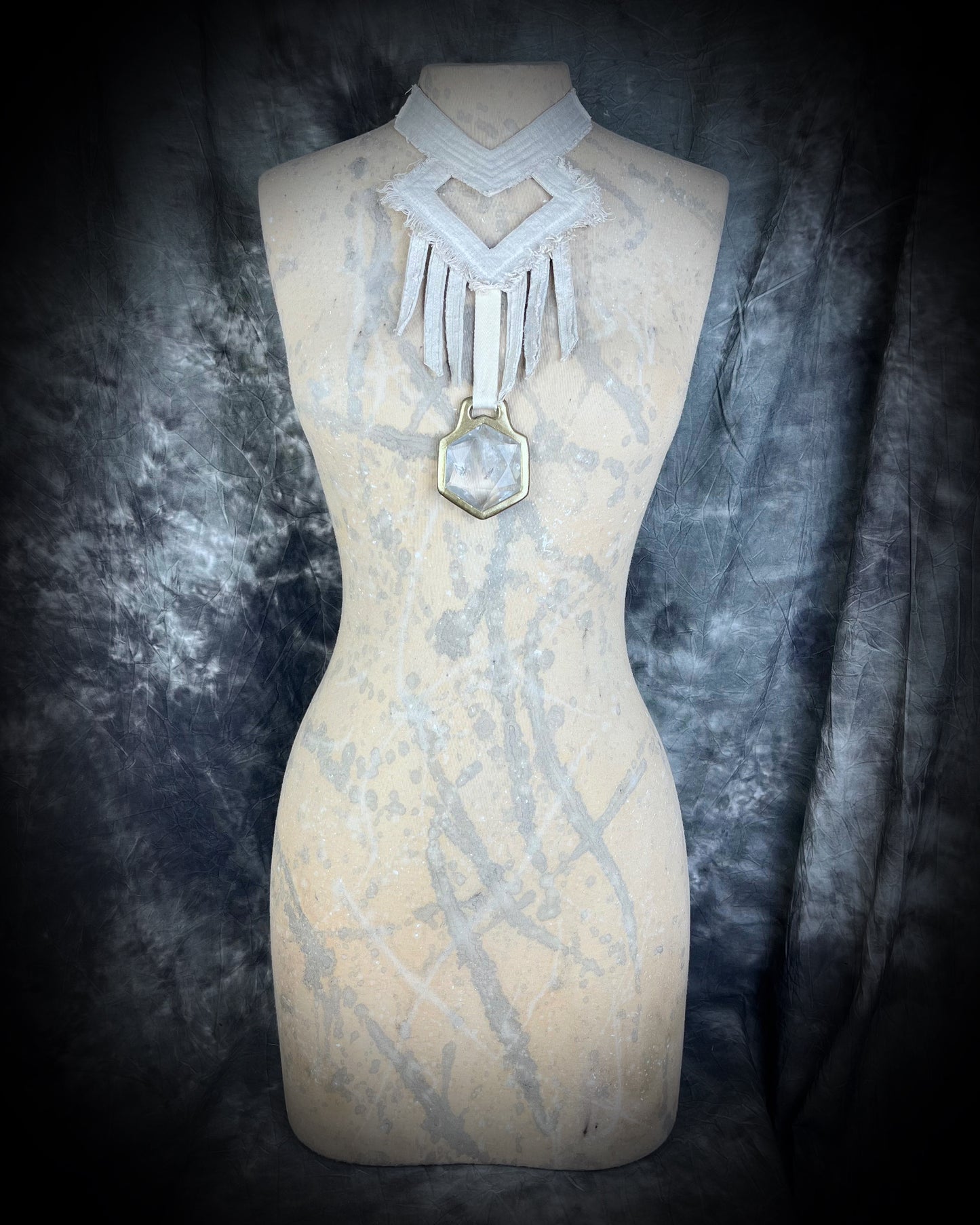 Shown on natural colored mannequin, a stunning handmade raw linen collar statement style necklace featuring a handcrafted quartz star of david hexagon crystal and geometric shapes and fringe. Wearable art for a boho free spirit or festival jewelry!