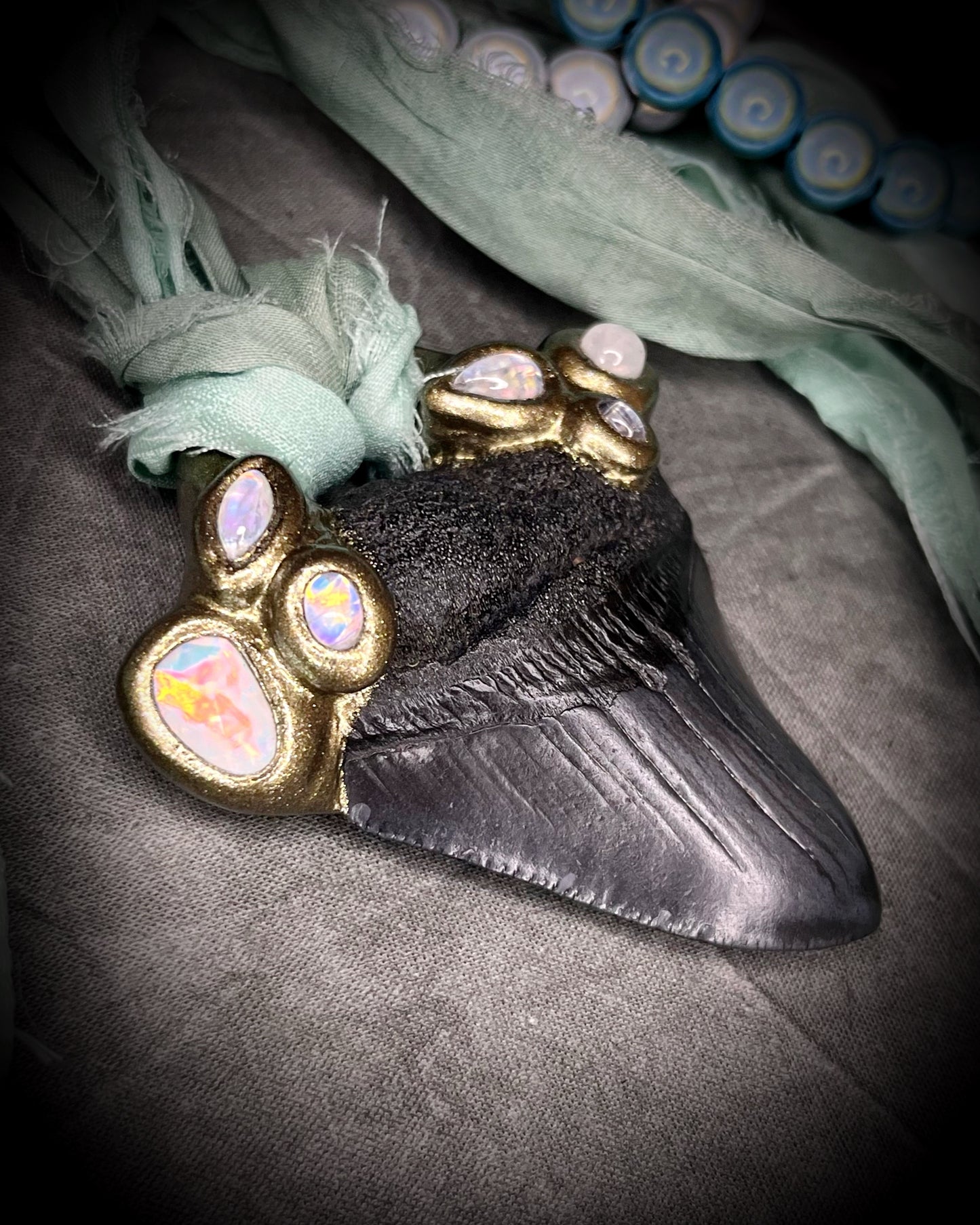 Megalodon shark tooth fossil handcrafted crystal talisman featuring opal gemstone and rainbow moonstones in gold, hung from recycled aqua silk. Beach wedding or summer jewelry photoshoot, cosplay, fantasy film costume or everyday enchantment!