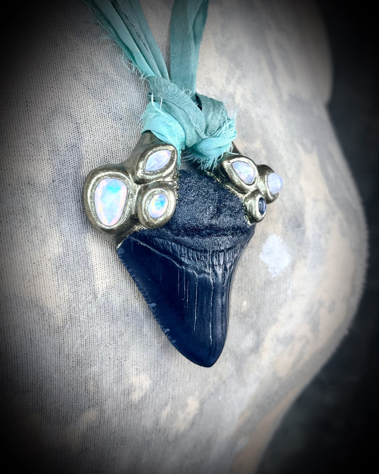 Megalodon shark tooth fossil handcrafted crystal talisman featuring opal gemstone and rainbow moonstones in gold, hung from recycled aqua silk. Beach wedding or summer jewelry photoshoot, cosplay, fantasy film costume or everyday enchantment!