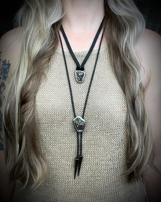 Meteorite bolo tie with gunmetal finish, black leather cord, and dramatic spike bolo tips, handmade by Become Spellbound in Baltimore, Maryland.