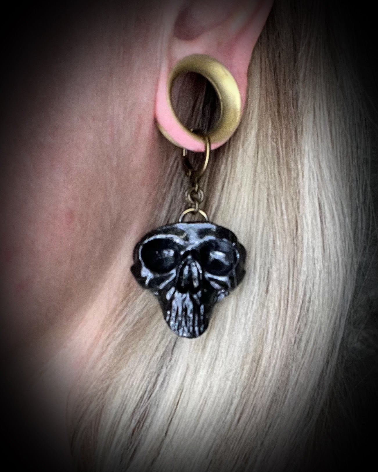 Model wearing sculptural black skull earrings on brass hooks — bold gothic statement jewelry for spooky season.