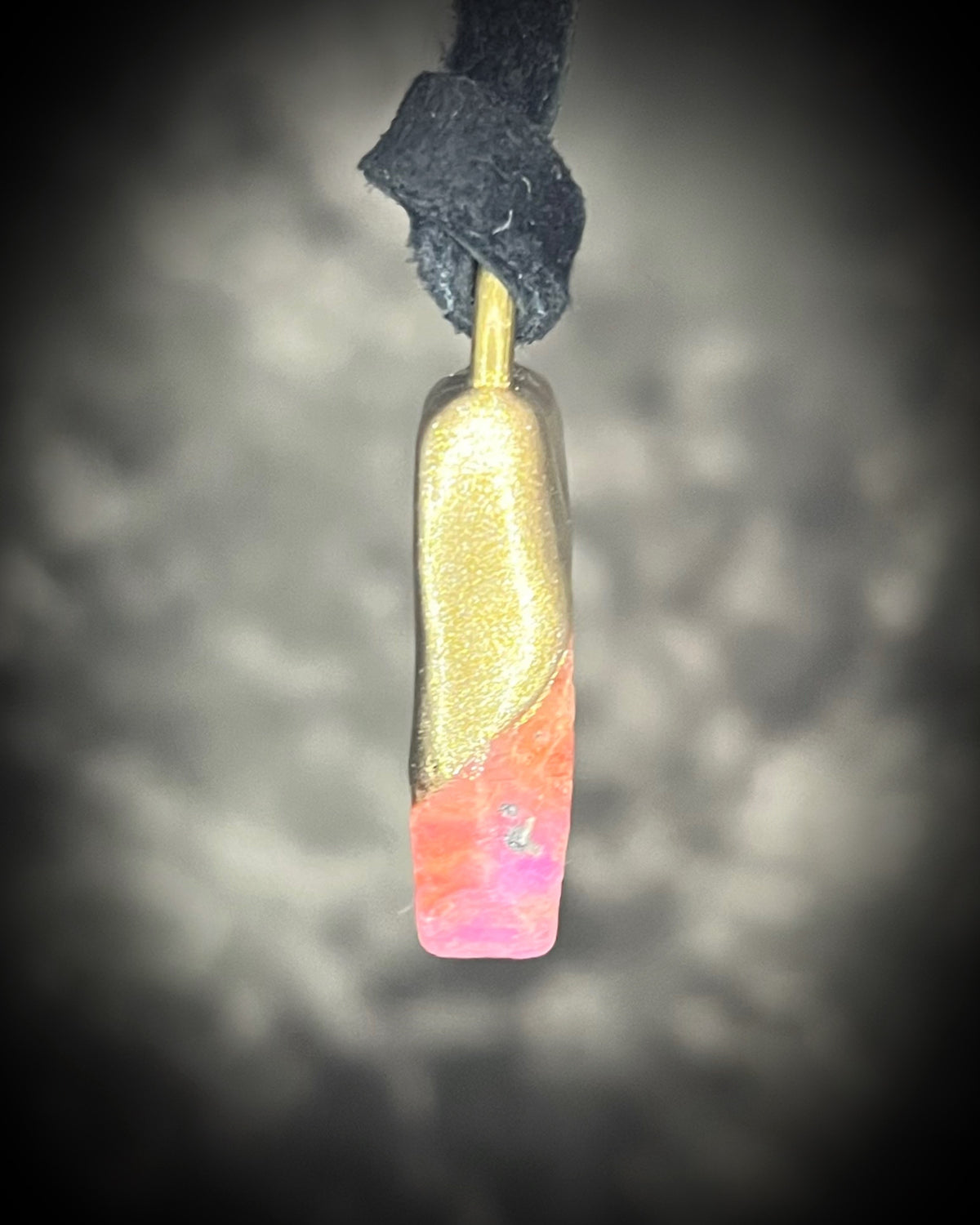 Raw ruby crystal talisman with natural texture in a sculptural gold-finish setting on black leather, handmade by Become Spellbound in Baltimore, Maryland.