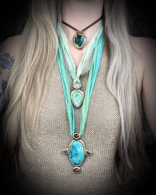 Regal handmade chrysocolla pendant adorned with 4 sparkling garnets in the cardinal directions. The Empress Talisman, gold finish artisanal pendant on soft aqua recycled silk. Statement jewelry for her.