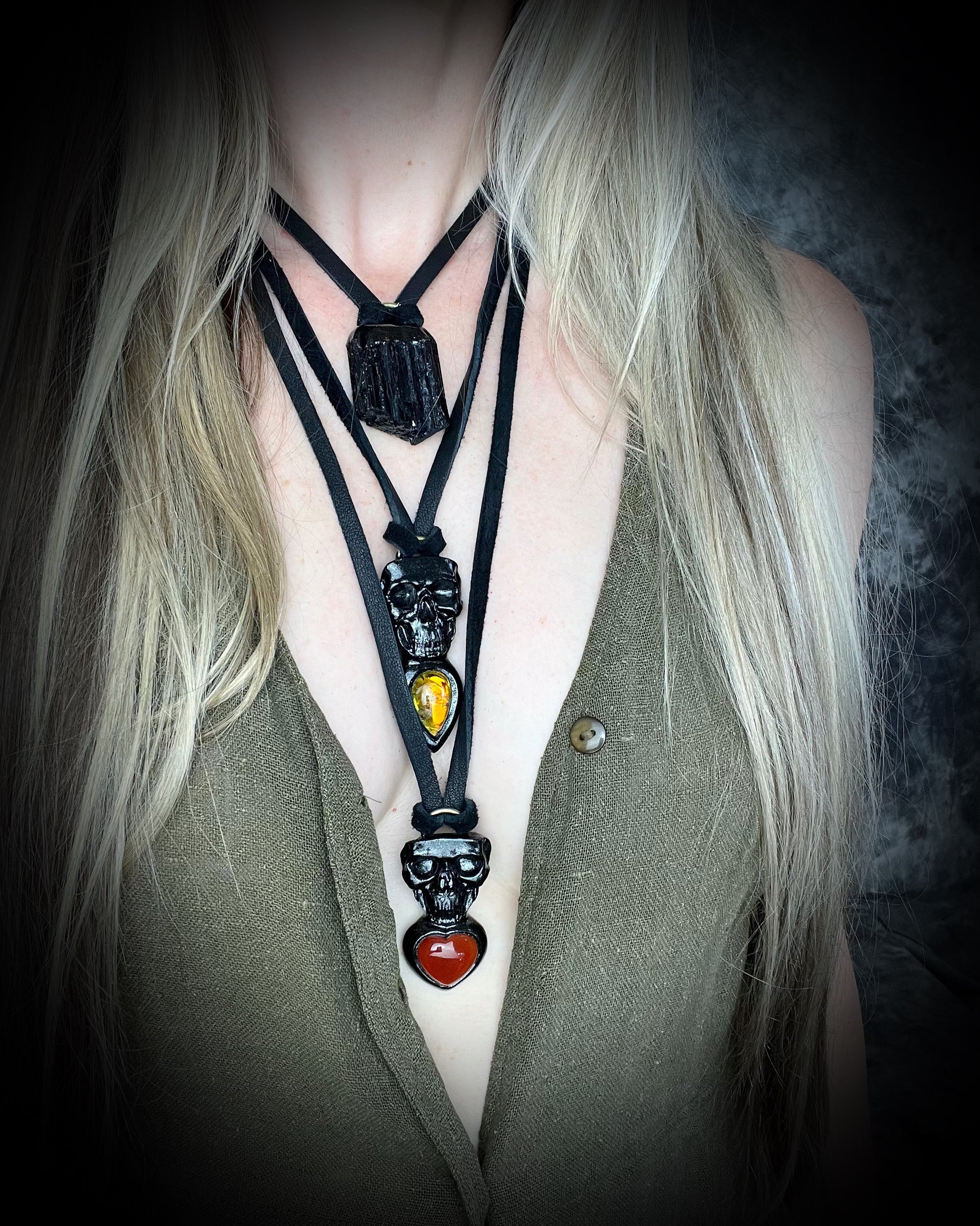 Skull-shaped pendant with a deep orange red carnelian heart shaped gemstone hung from black leather. Halloween jewelry for her, gothic jewelry gift for her.