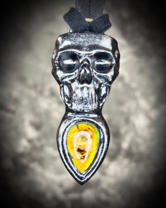 Skull-shaped pendant with a yellow fire citrine teardrop shaped gemstone on a dark background. Halloween jewelry for her, gothic jewelry gift for her.