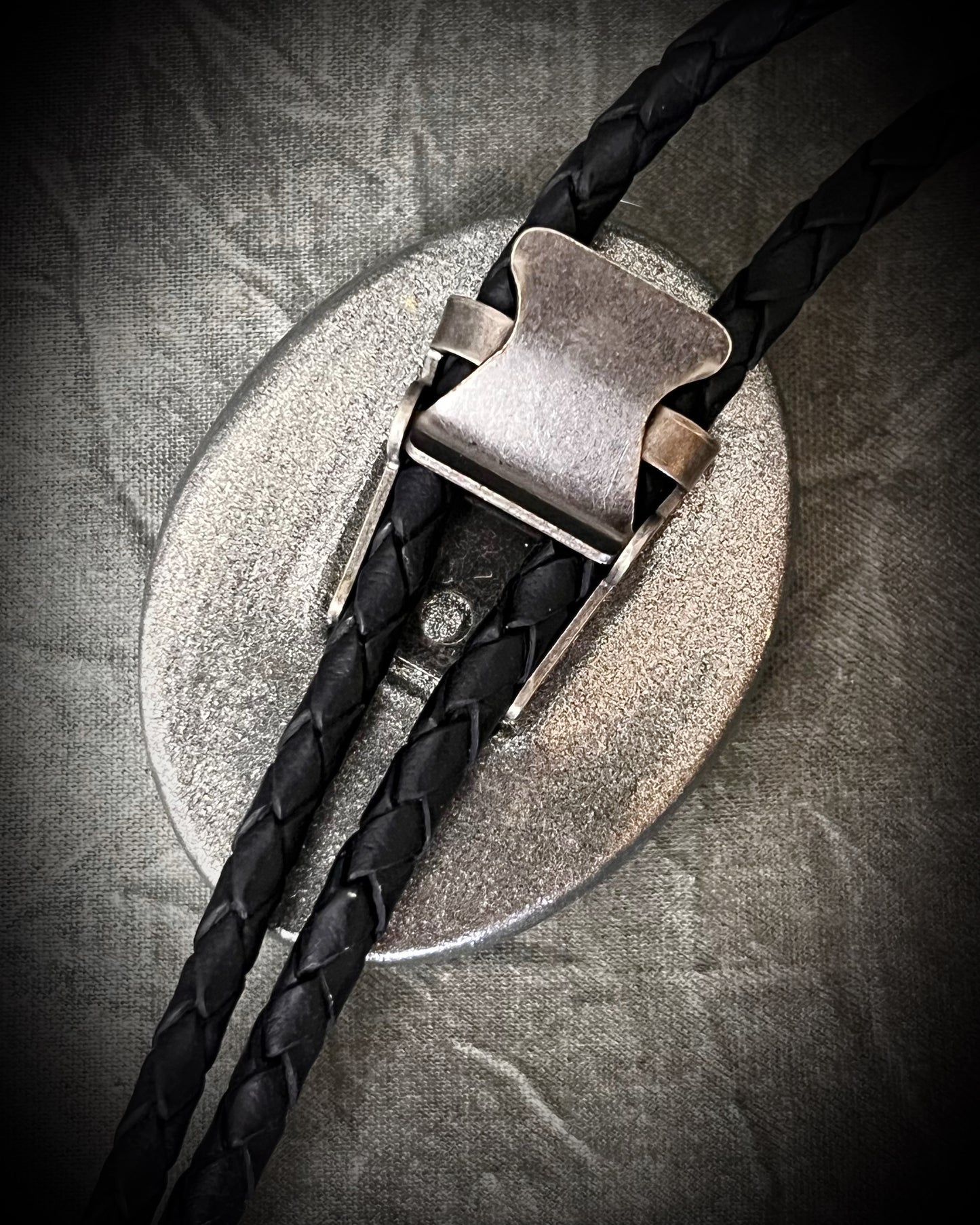 Stormy cool tone flashy labradorite crystal bolo tie in a gunmetal finish. Men's crystal jewelry trends and western inspired fashion 2026. Closeup of back bolo clasp.