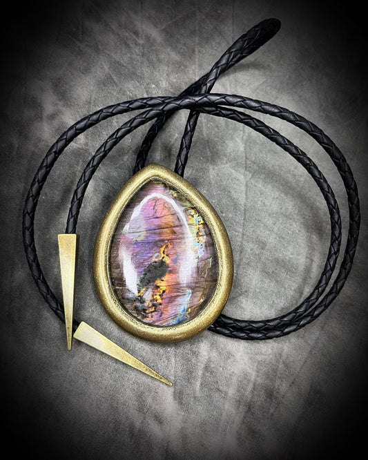 XL teardrop labradorite bolo tie with vivid sunset flashes of purple, orange, yellow, pink, and blue in a gold finish with brass spike tips.
