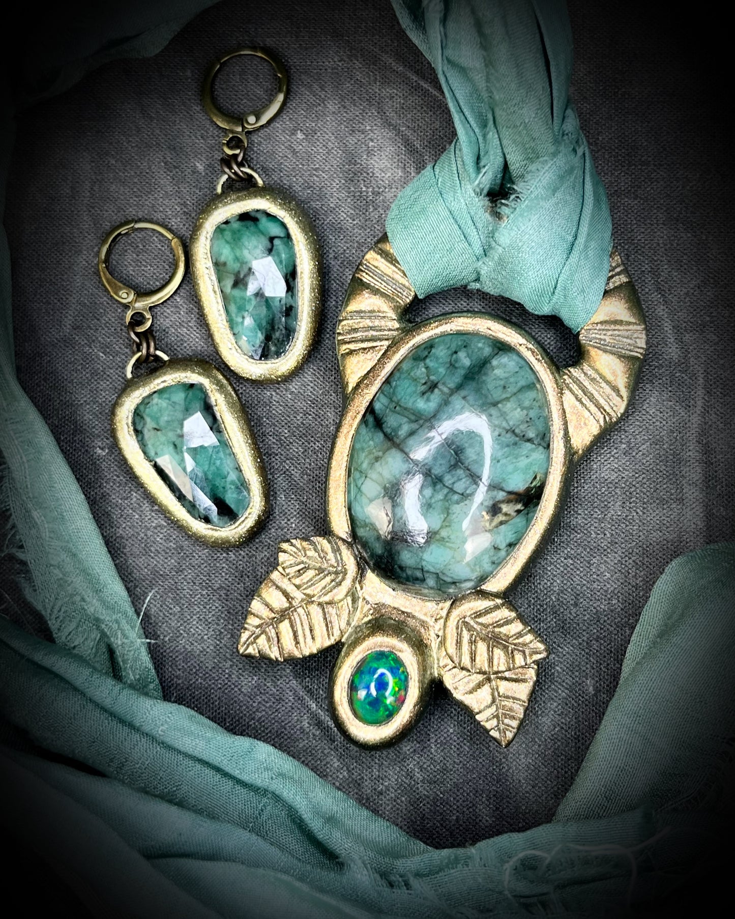 Emerald and black opal gemstone necklace in a luxe gold setting, crafted on aqua recycled silk. One-of-a-kind crystal healing pendant, sustainable and perfect for 2025 gifting. Shown here with gold emerald matching earrings.