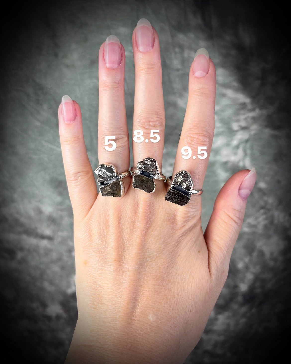 Three sterling silver multi-stone rings for women featuring moldavite crystal and a genuine iron meteorite from outerspace shown worn on a hand in sizes 5, 8.5 and 9.5.