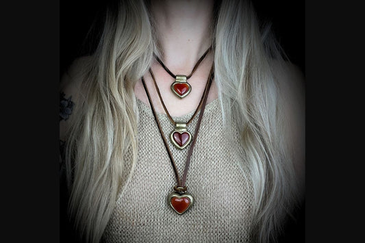 Carnelian is the Crystal of the Year 2026 blog post feature image of a woman with long hair wearing 3 layering necklaces that are carnelian heart pendants.