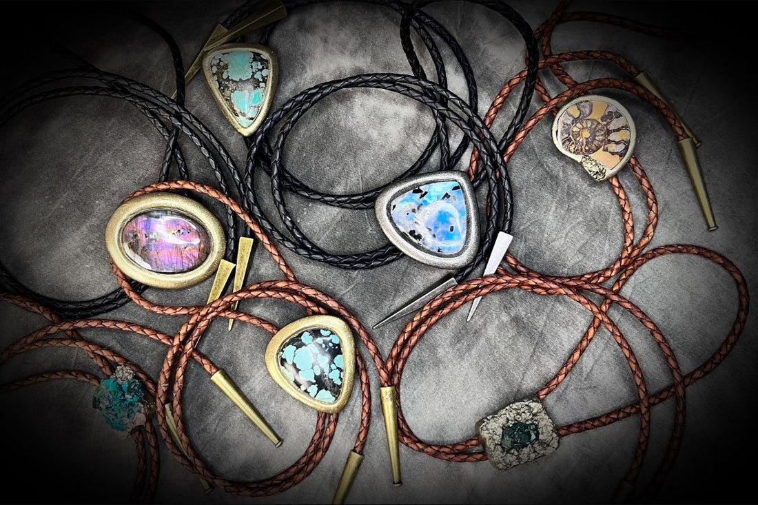 Outlaws + Oracles: A Bold New Take on Crystal Bolo Ties. An image of various colorful gemstone bolo ties on black and brown leather on a neutral backdrop.