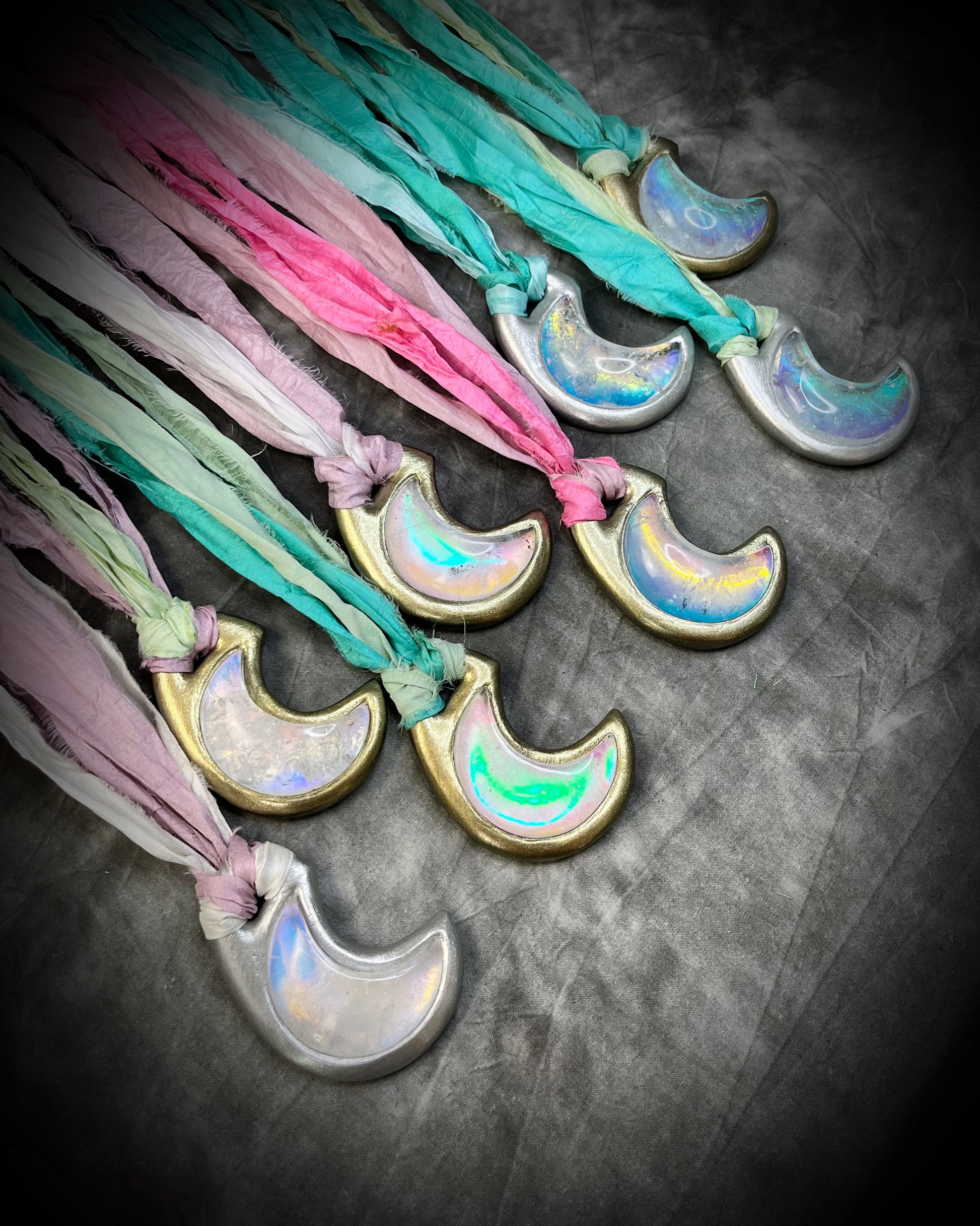 Multiple opalescent crescent moon quartz gemstone handmade crystal healing jewelry necklaces on recycled silk in shades of pink, mint green, turquoise, lilac and finished in gold or silver.  All with eco-friendly recycled silk and an opal pendant glow.