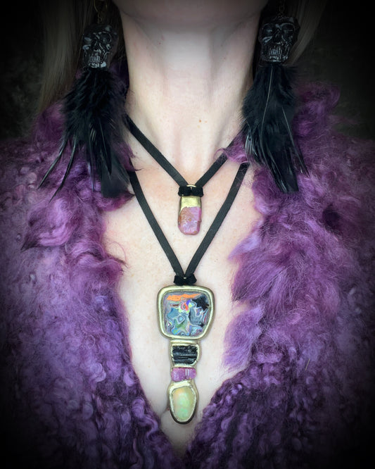 Raw ruby crystal talisman with natural texture in a sculptural gold-finish setting on black leather, handmade by Become Spellbound in Baltimore, Maryland.