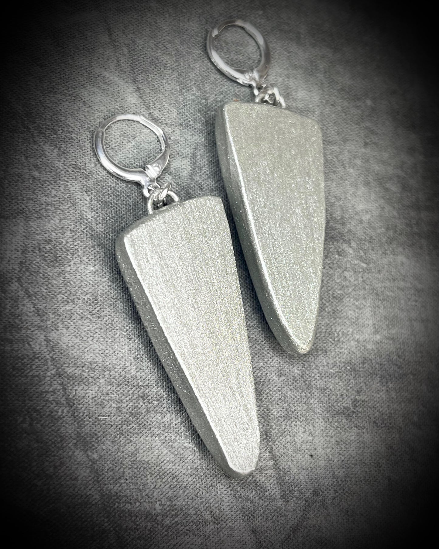 Pair of silver earrings on a textured gray surface