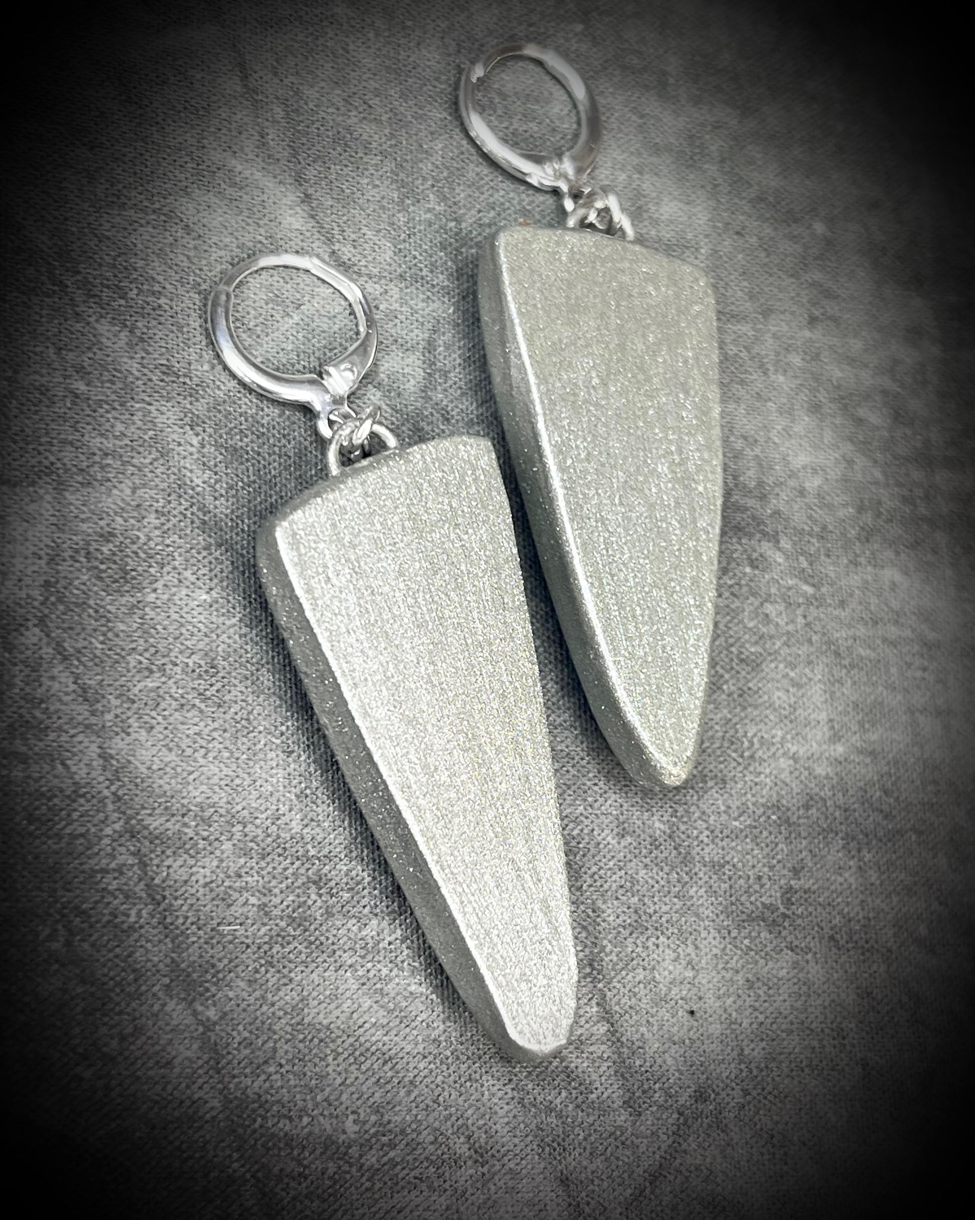 Pair of silver earrings on a textured gray surface