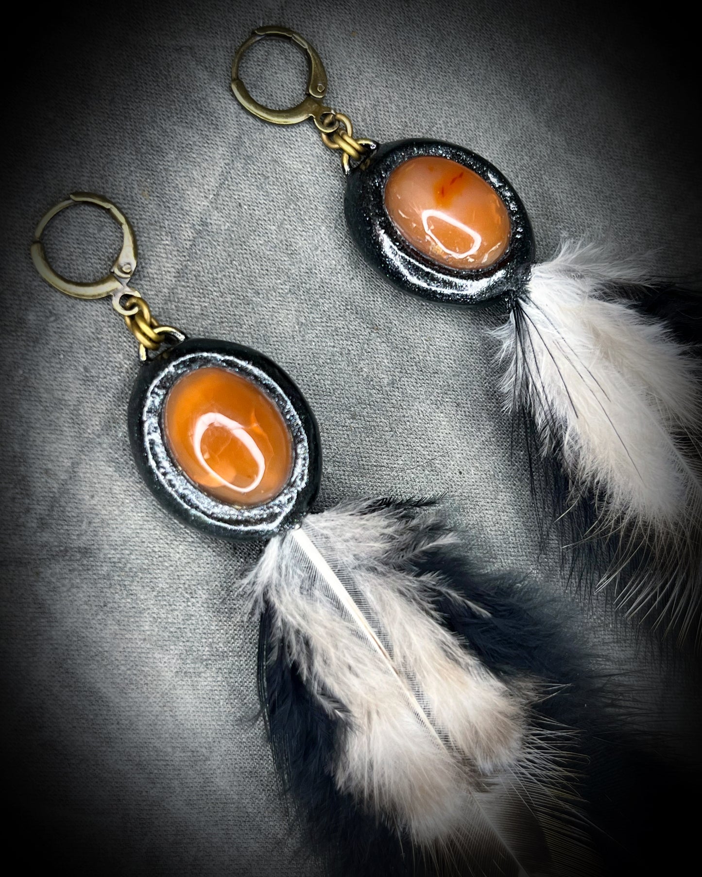Closeup of  Handmade Carnelian crystal jewelry,  feather birthstone carnelian gemstone danngle earrings with brass huggie ear hooks.  Dangle drop earrings for gift for her, summer, fall, festivals and birthstone jewelry for Virgo. 
