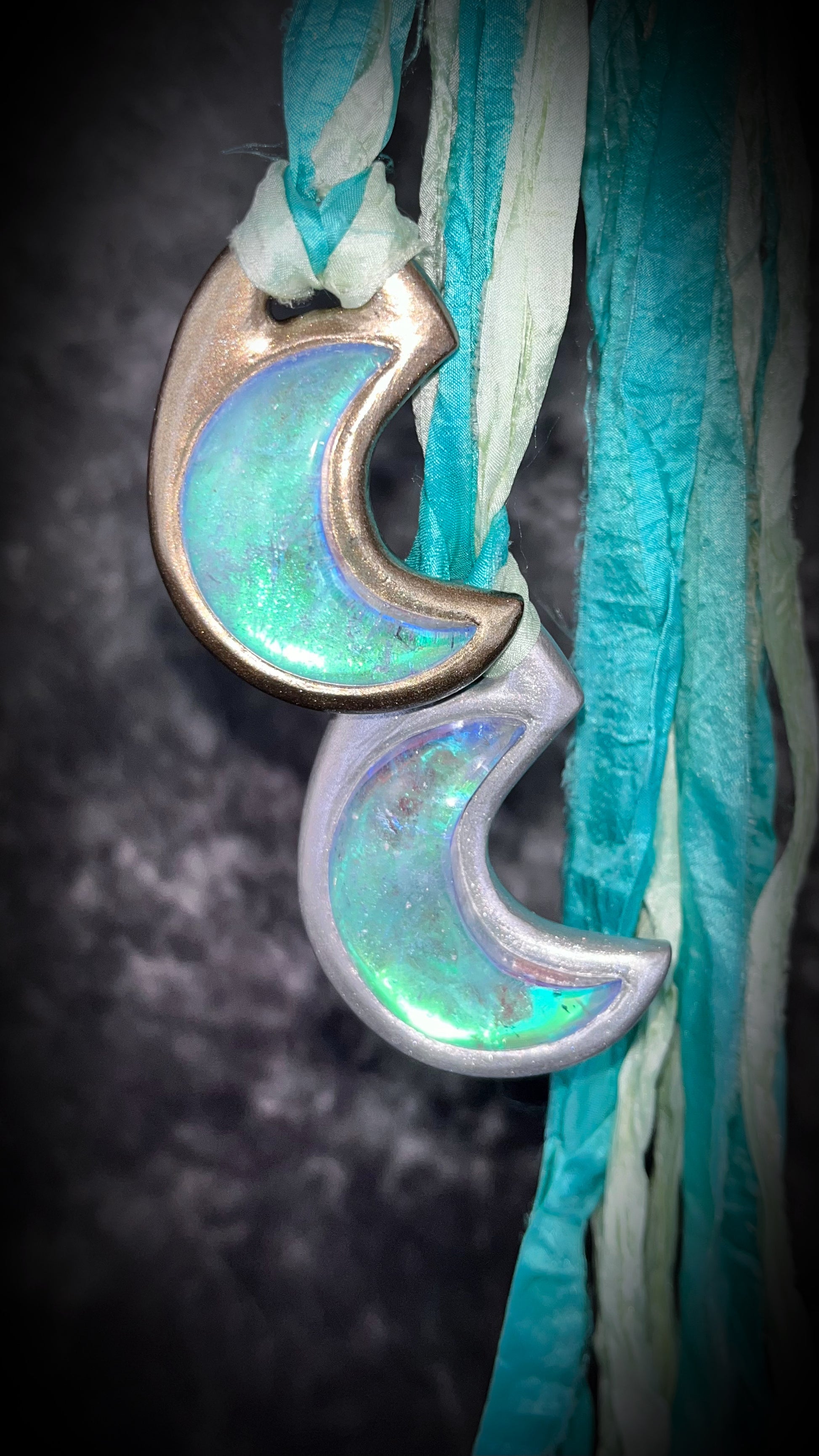 Handmade designer glowing green turquoise opalescent quartz gemstone crescent moon pendants in a silver and gold finish.  This crystal healing necklace is strung from aqua and mint green recycled silk for the eco-friendly jewelry collector.  