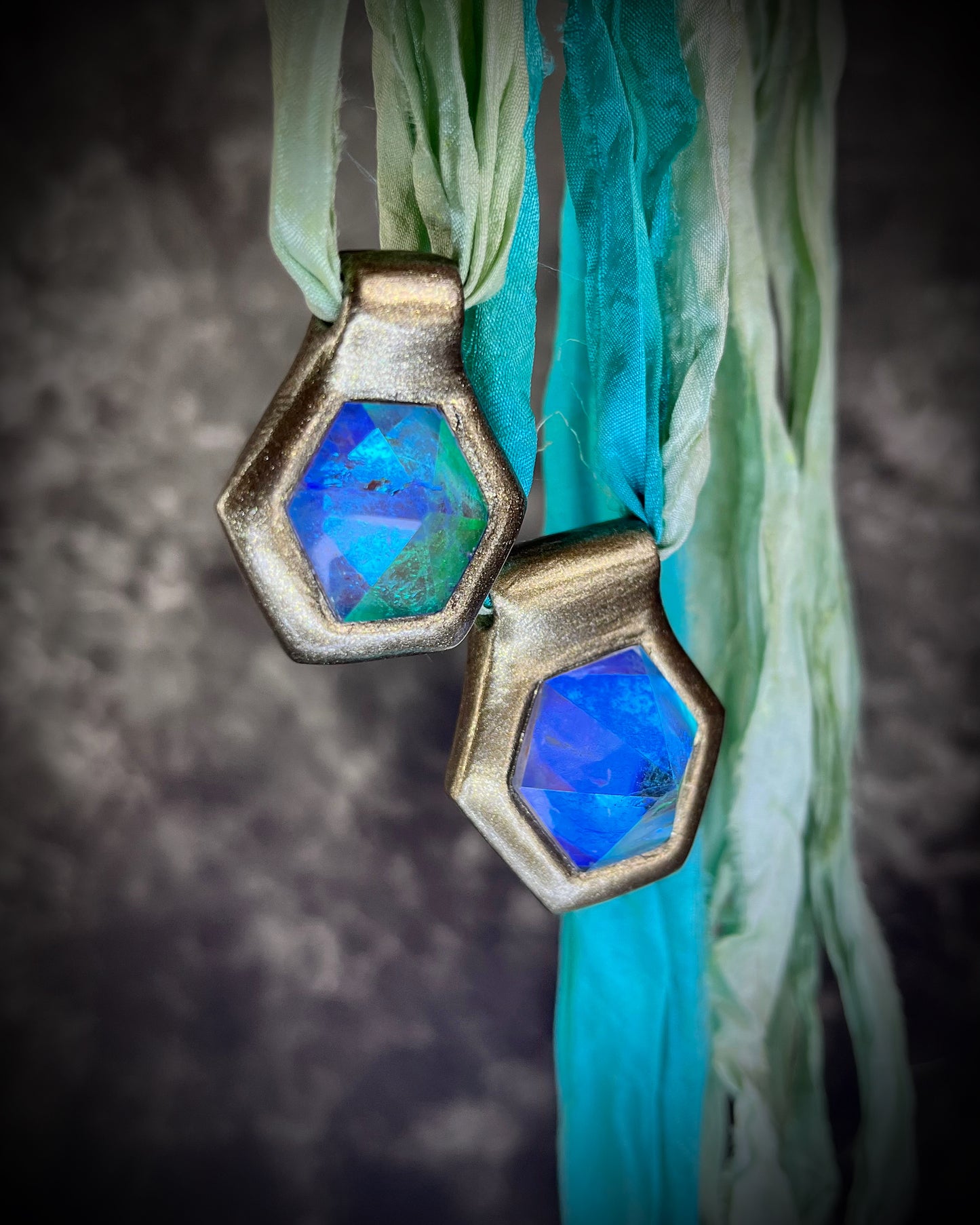 Side view of blue handmade designer aqua turquoise opalescent quartz gemstone pendants in a gold finish.  These crystal healing necklaces are customizable and can be strung from leather or sea green recycled silk for the sustainable and eco-friendly jewelry lover or mermaid.