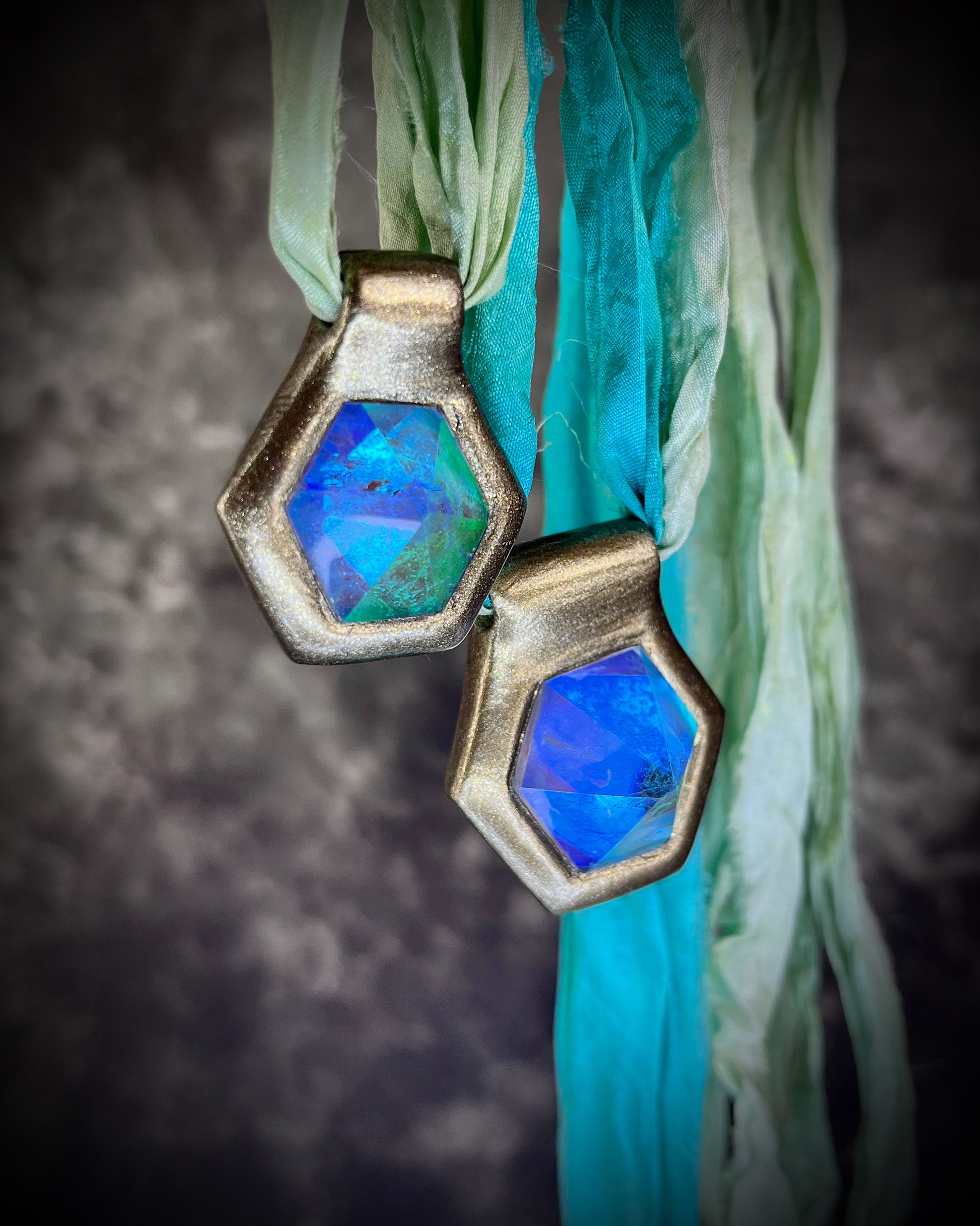 Side view of blue handmade designer aqua turquoise opalescent quartz gemstone pendants in a gold finish.  These crystal healing necklaces are customizable and can be strung from leather or sea green recycled silk for the sustainable and eco-friendly jewelry lover or mermaid.
