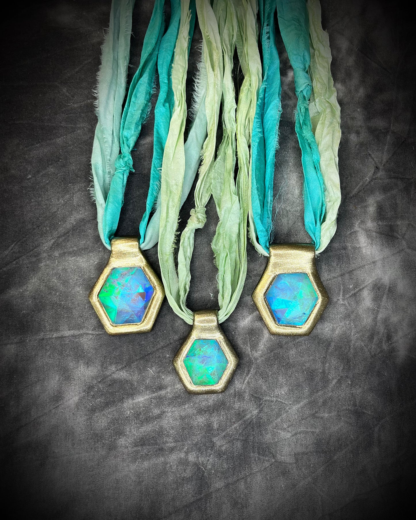 Three sparkling handmade designer aqua turquoise opalescent quartz gemstone pendants in a gold finish.  These crystal healing necklaces are customizable and can be strung from leather or sea green recycled silk for the sustainable and eco-friendly jewelry lover or mermaid.