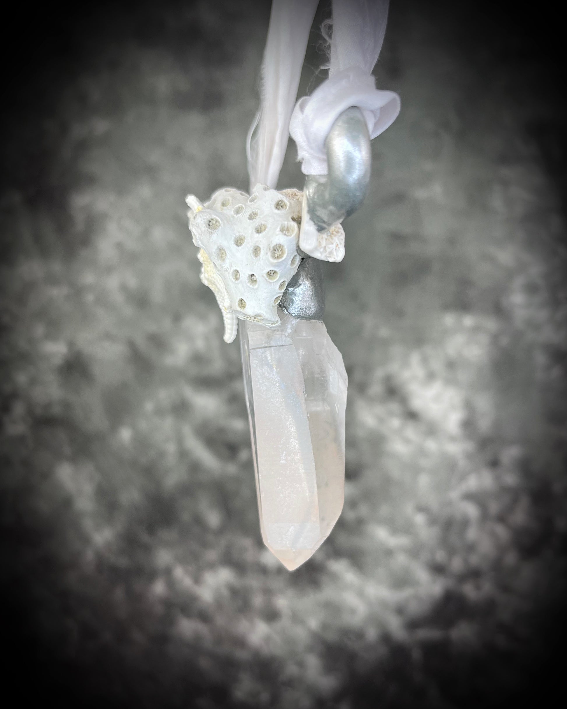 Side view of silver handmade designer bridal or beach bride necklace featuring quartz crystal, white fossilized coral, starfish, seashell and is strung from recycled white silk for an eco-friendly summer beach wedding elegance.  