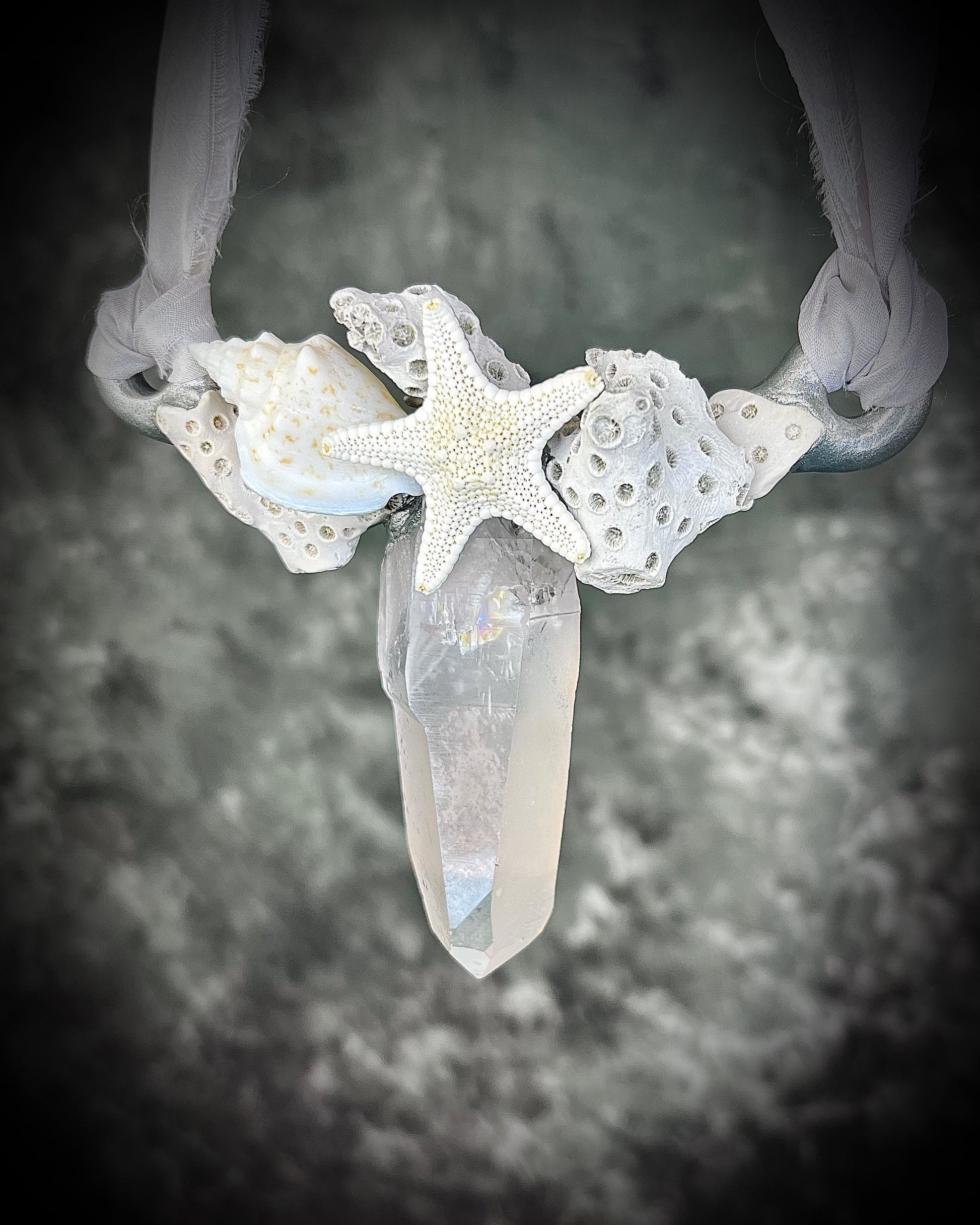 Handmade designer bridal or beach bride necklace in silver finish featuring quartz crystal, white fossilized coral, starfish, seashell and is strung from recycled white silk for an eco-friendly summer beach wedding elegance.  