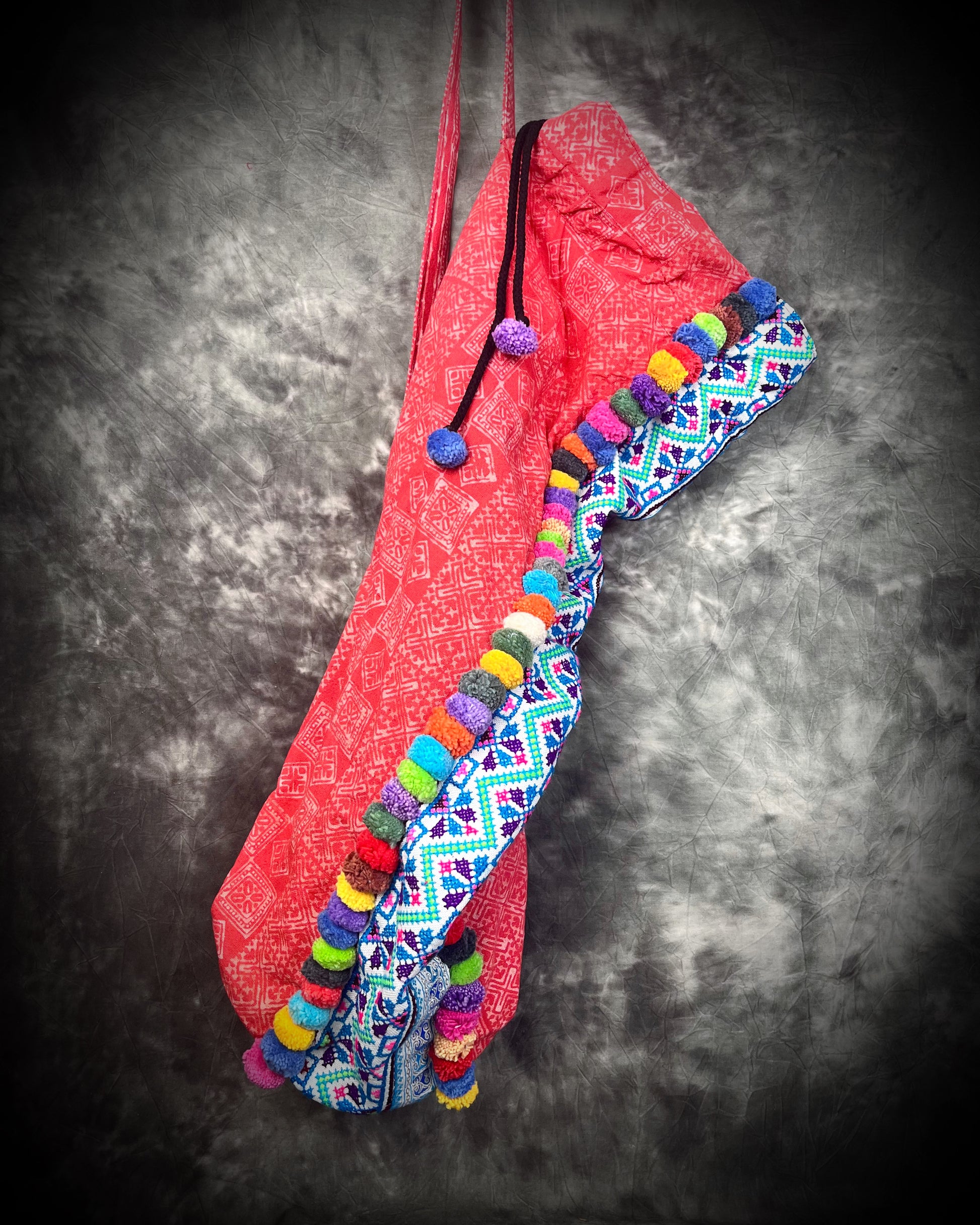 Artisanal handmade thailand tribal pom pom yoga mat bag in red with colorful fabric and rainbow details. The perfect yoga accessory for the boho traveler!