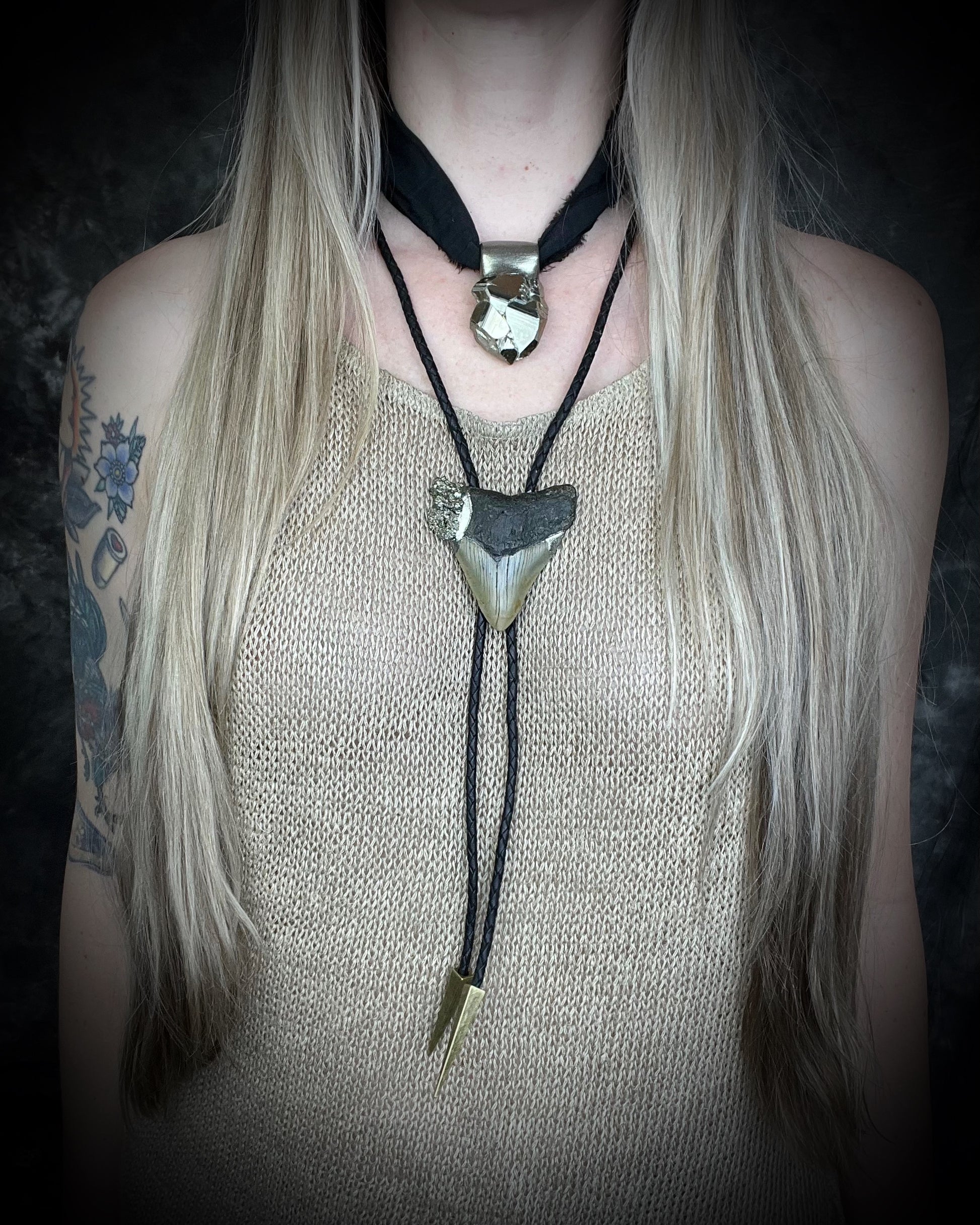 A prehistoric Megalodon tooth bolo tie set in a rugged metallic finish, adorned with shimmering Pyrite crystals layered with another pyrite pendant.