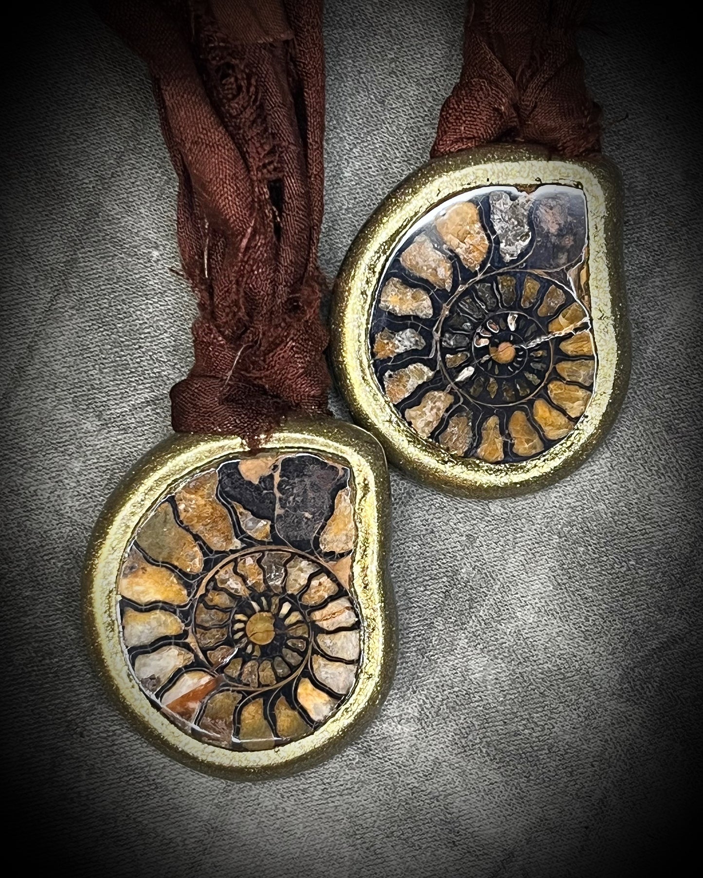 Ammonite fossil necklace featuring an ancient spiral fossil suspended from brown recycled silk, handmade by Become Spellbound in Baltimore, Maryland. Here with a matching pendant. 