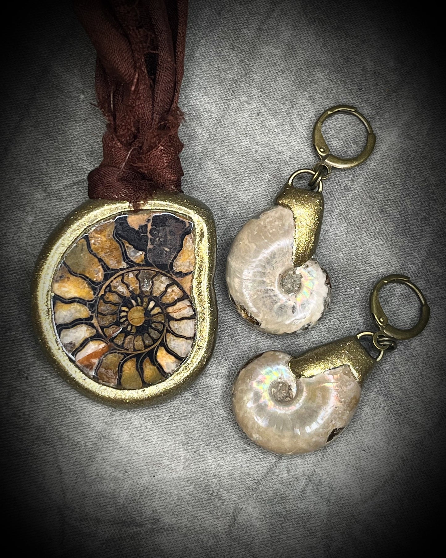 Ammonite fossil necklace featuring an ancient spiral fossil suspended from brown recycled silk, handmade by Become Spellbound in Baltimore, Maryland. Here with ammonite earrings. 