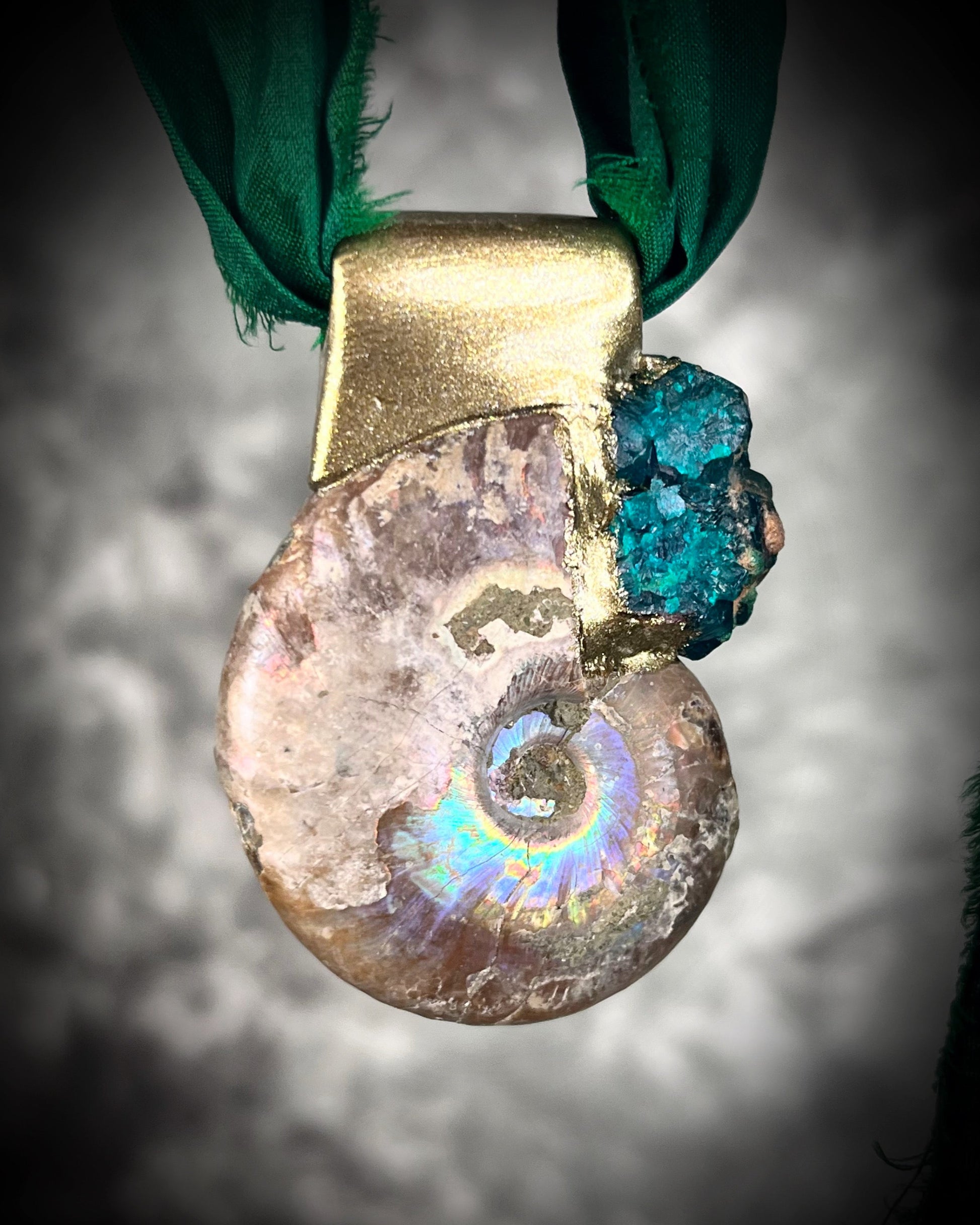 Ammonite fossil pendant with turquoise dioptase gemstones in a gold finish, on an earthy brown leather cord. Fossil healing jewelry for transformation for him or her. 
