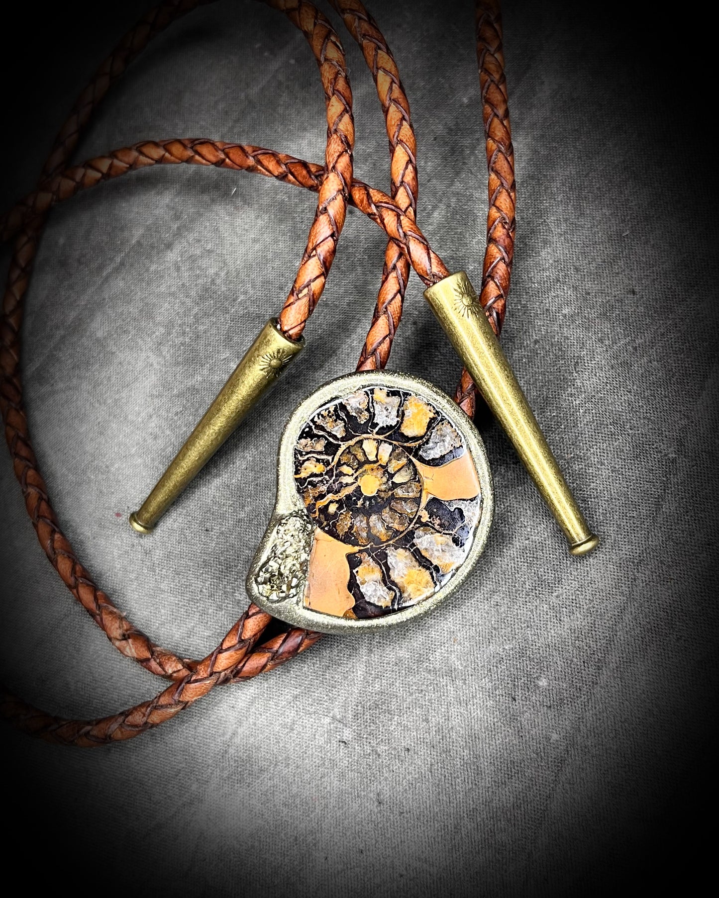 Ammonite fossil with pyrite bolo tie on brown braided leather with brass tips — fantasy bohemian western jewelry.