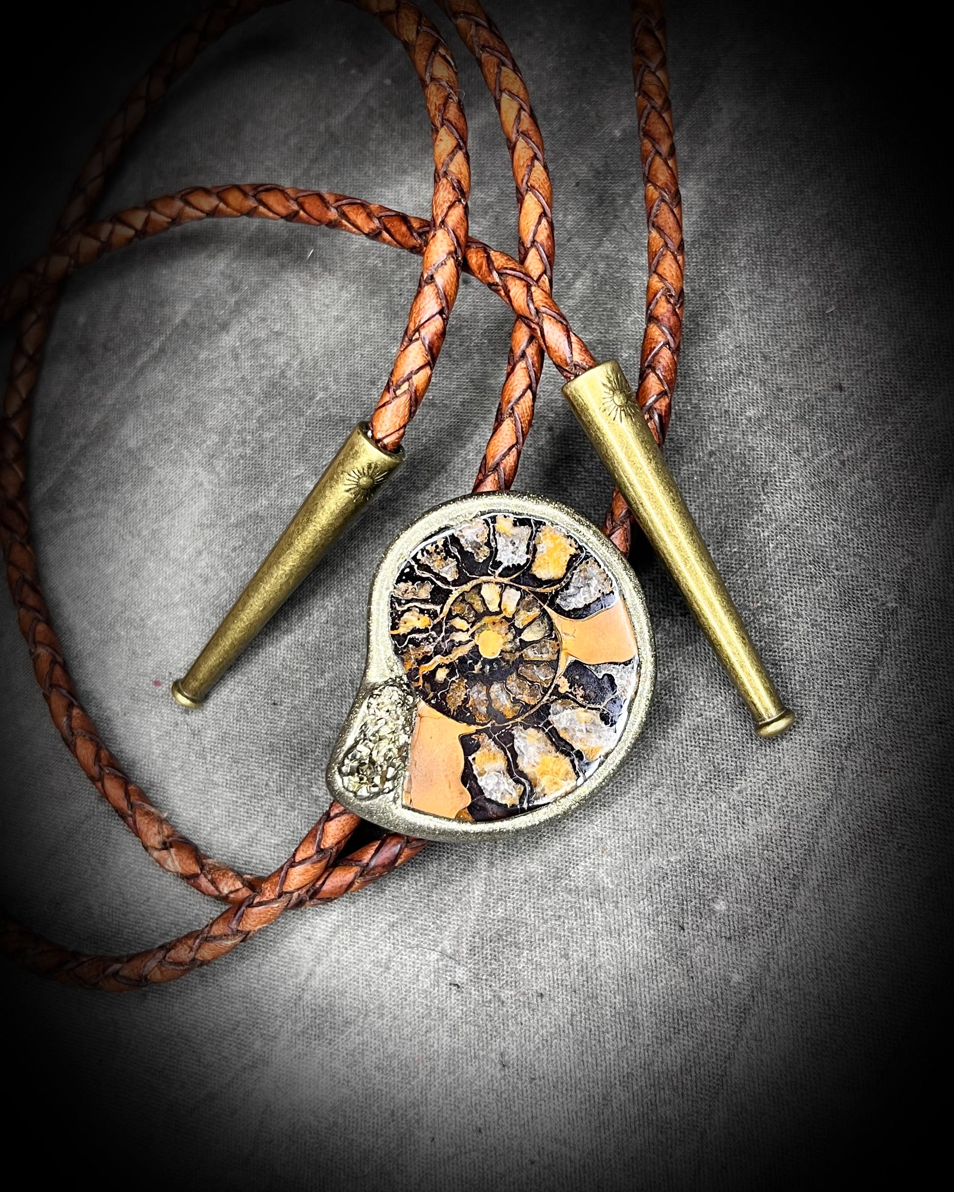Ammonite fossil with pyrite bolo tie on brown braided leather with brass tips — fantasy bohemian western jewelry.
