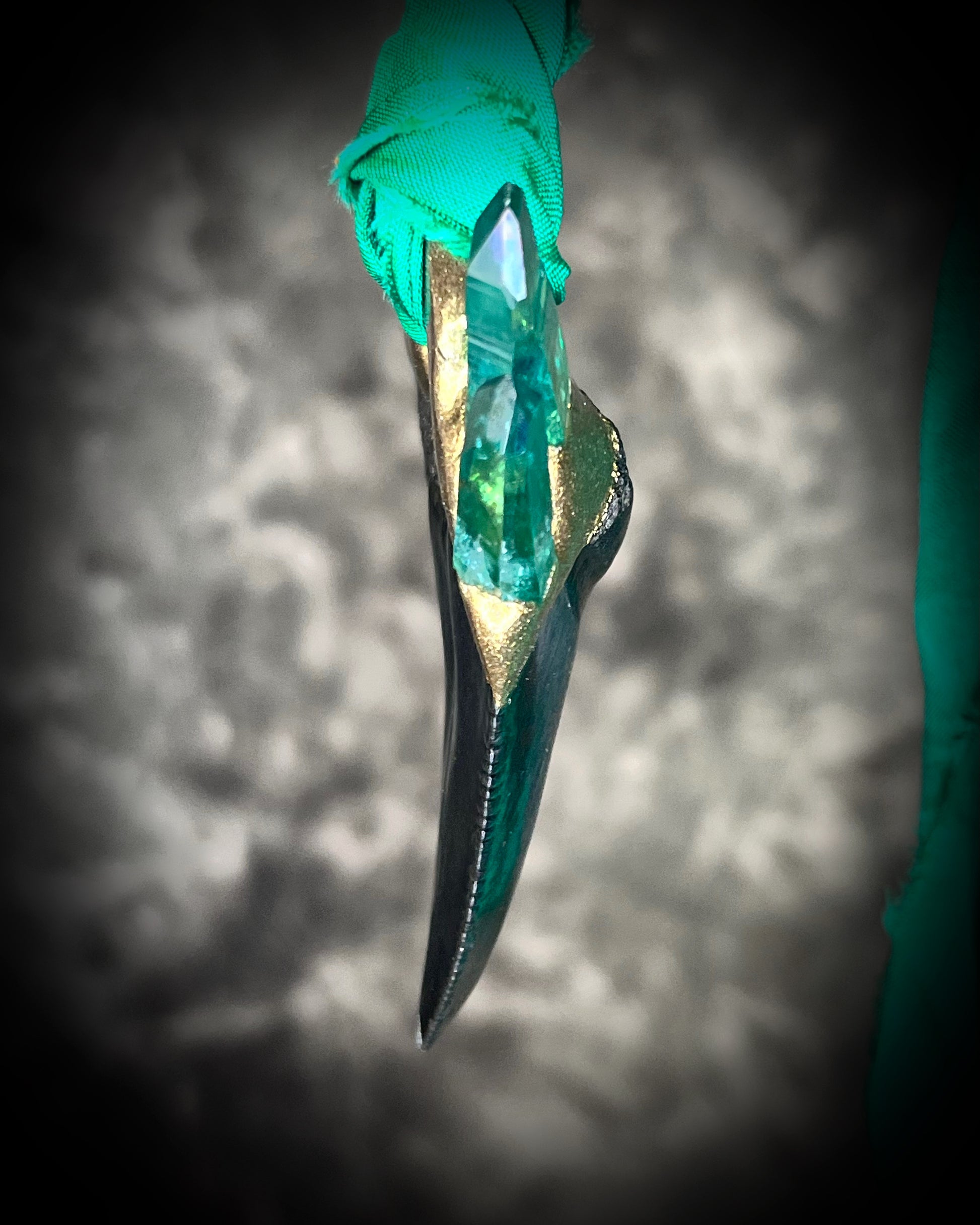 Side view of Ancient megalodon fossil tooth necklace with green aura quartz points, hung from sustainable green recycled silk.