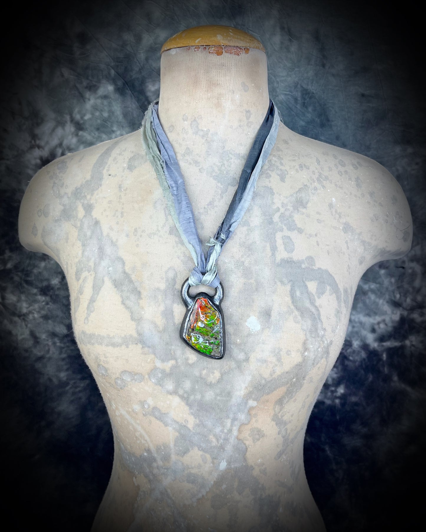 Mannequin wearing a necklace with a pendant on a dark background