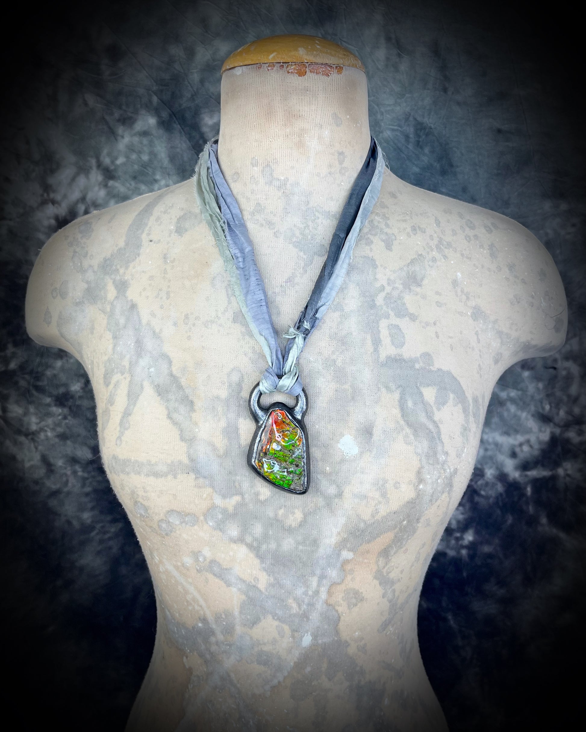 Mannequin wearing a necklace with a pendant on a dark background