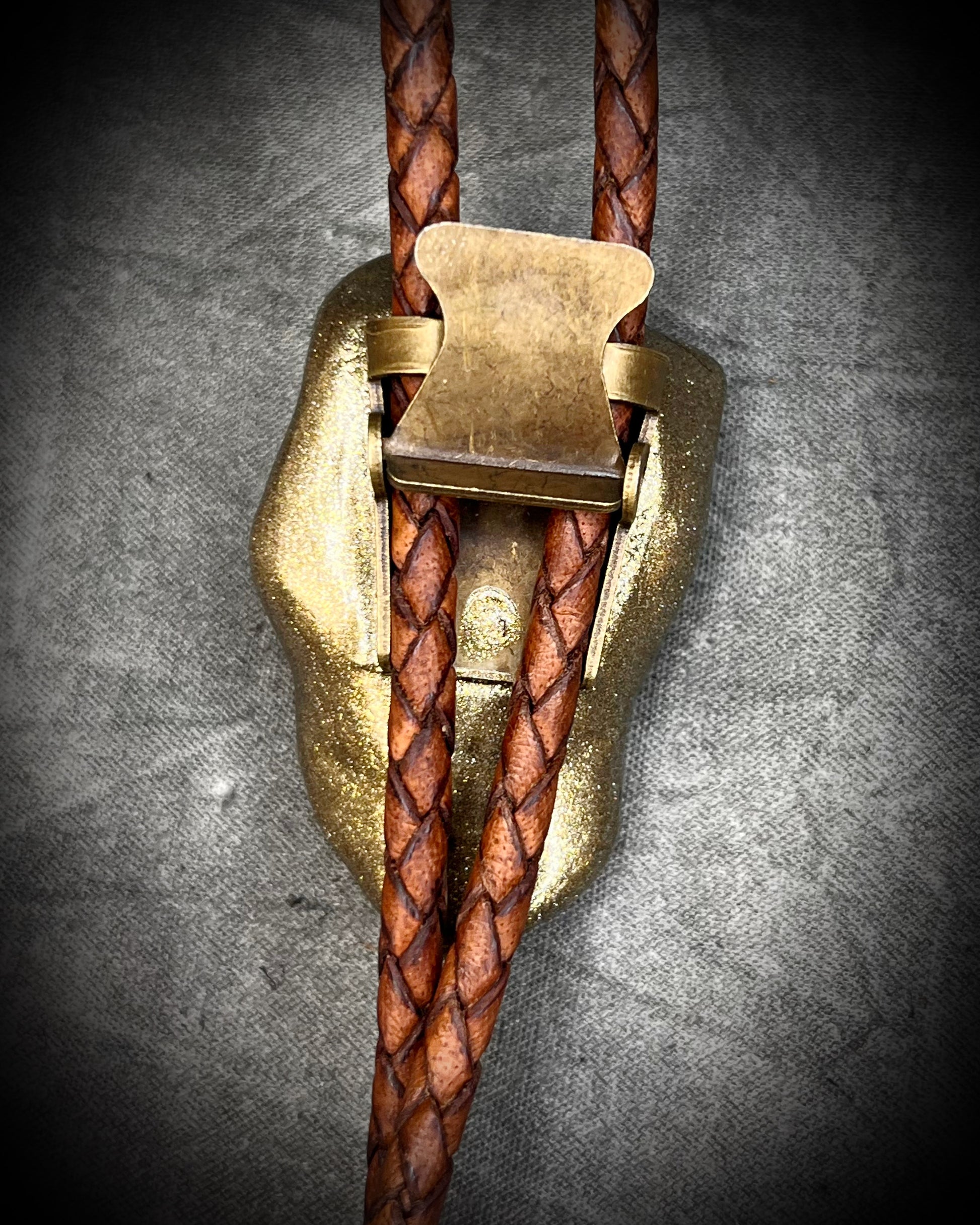 Back view bolo clasp of Raw Dioptase teal colored gemstone Bolo tie set in a gold finish and mounted on earthy brown leather. A talisman for heart chakra healing, crystal jewelry for him. Western 2026 jewelry trend bolo. 