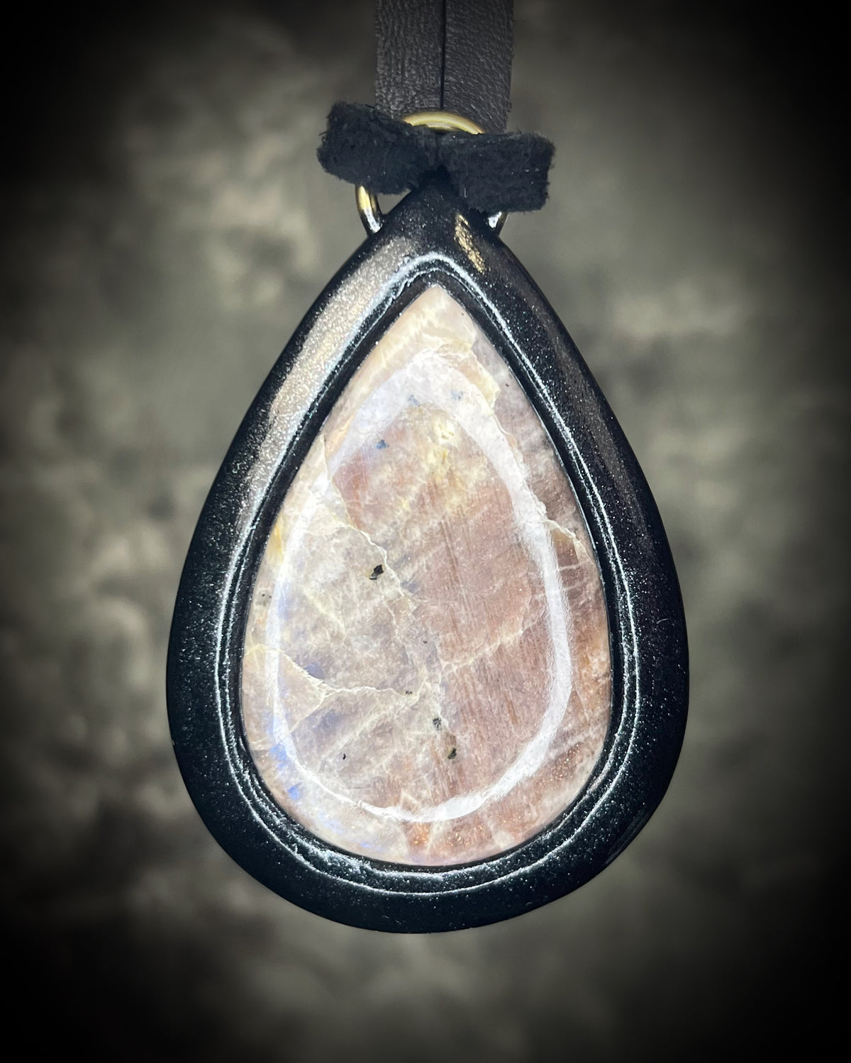 Belomorite sunstone moonstone teardrop pendant with shimmering feldspar color in a sculptural black-finish setting on black leather, handmade by Become Spellbound in Baltimore, Maryland.