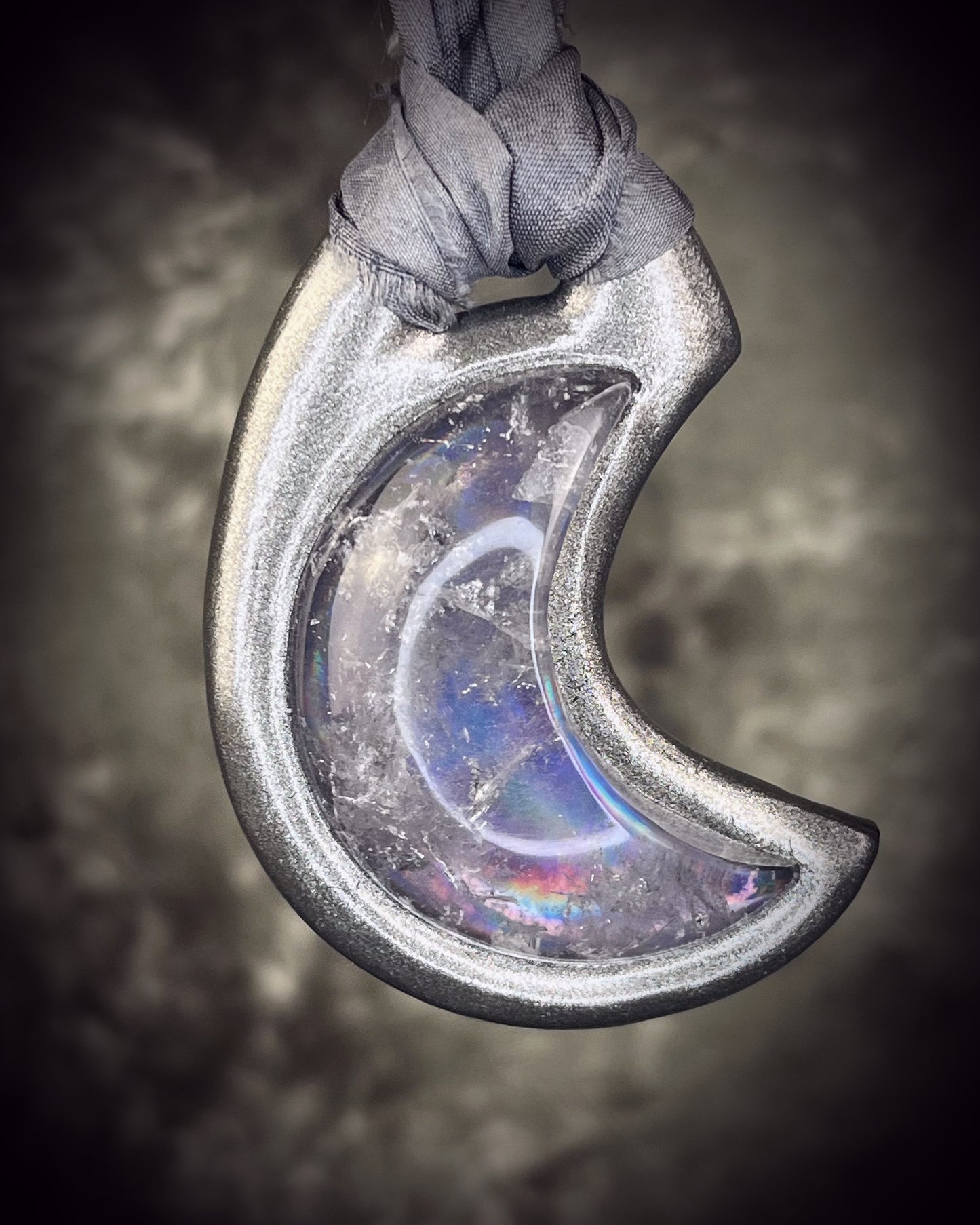 Black rainbow quartz crescent moon talisman on recycled silk with dark iridescent rainbow flashes, handcrafted by Become Spellbound.